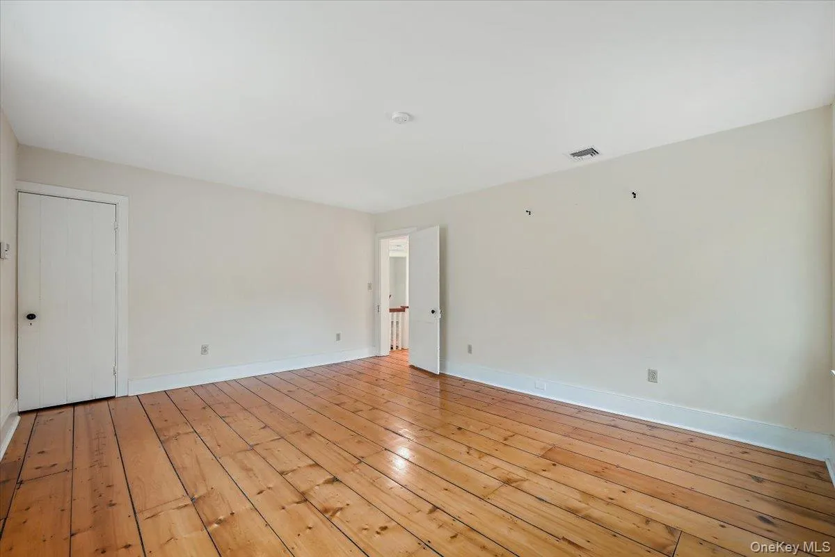 Unfurnished room with light wood finished floors and baseboards Unfurnished room with light wood finished floors and baseboards