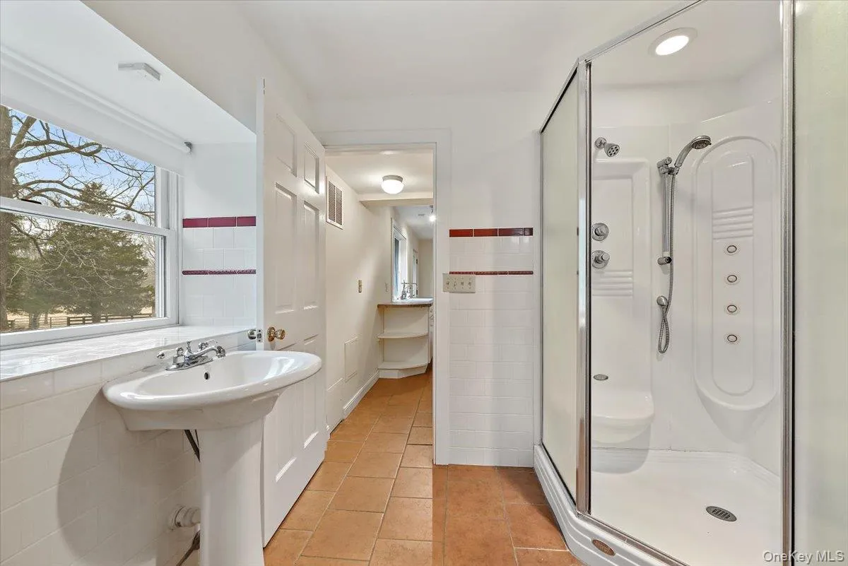 Full bathroom with light tile patterned flooring, a shower stall, and tile walls Full bathroom with light tile patterned flooring, a shower stall, and tile walls