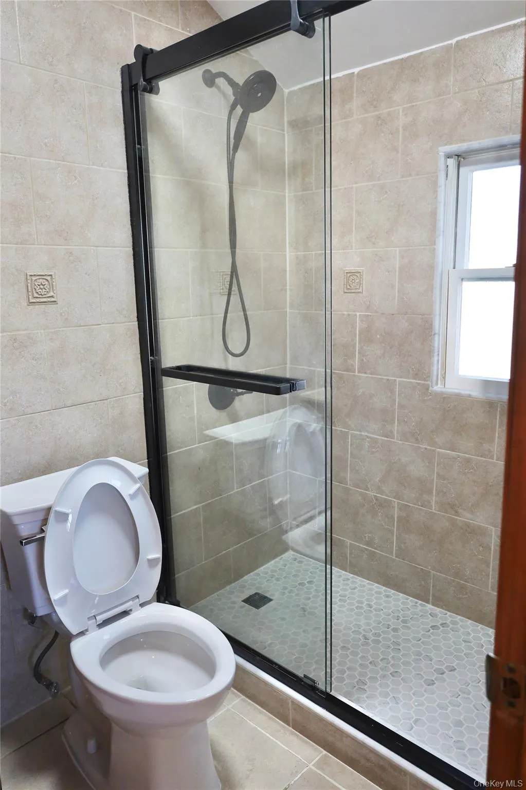 Full bath with tile patterned flooring, a stall shower, and tile walls Full bath with tile patterned flooring, a stall shower, and tile walls