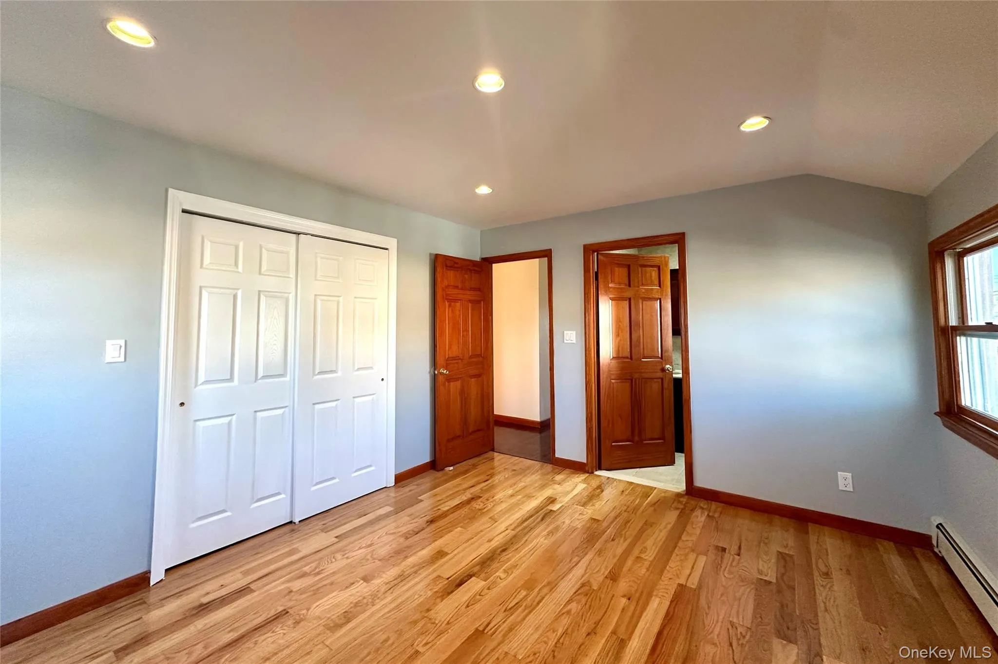 Unfurnished bedroom featuring recessed lighting, a baseboard radiator, light wood finished floors, and a closet Unfurnished bedroom featuring recessed lighting, a baseboard radiator, light wood finished floors, and a closet