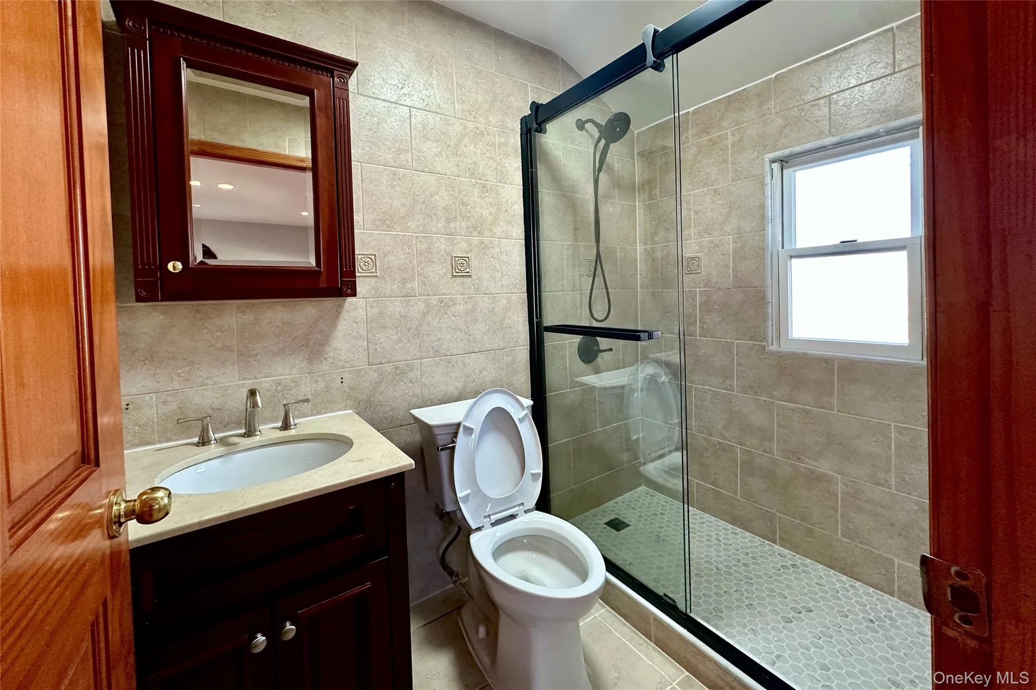 Full bath featuring tile walls, vanity, a shower stall, and backsplash Full bath featuring tile walls, vanity, a shower stall, and backsplash