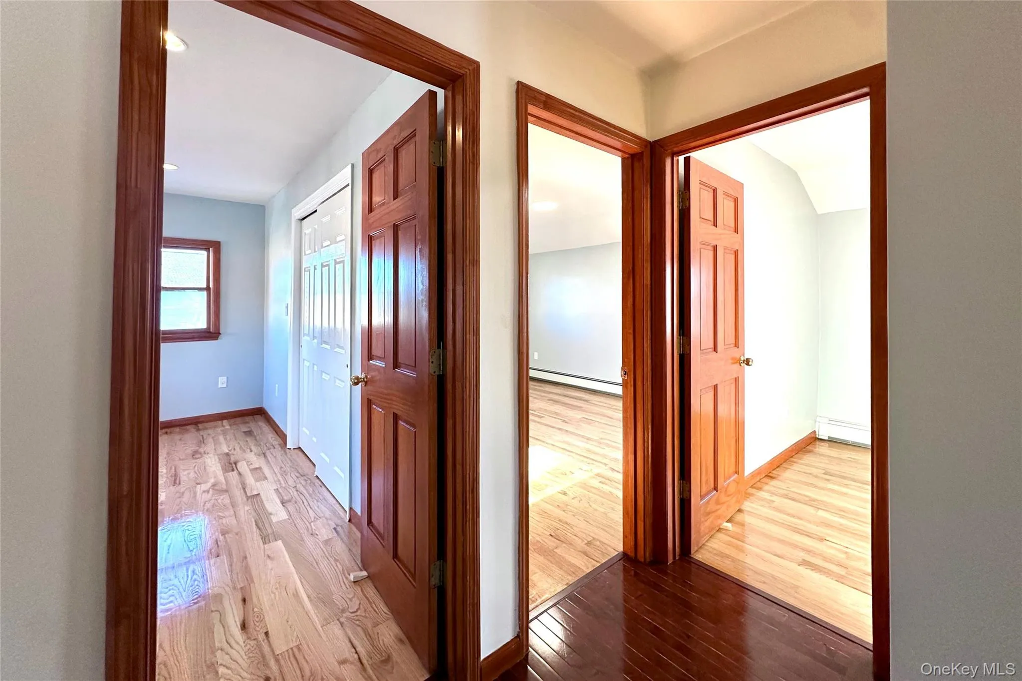Corridor with light wood-style flooring and baseboard heating Corridor with light wood-style flooring and baseboard heating
