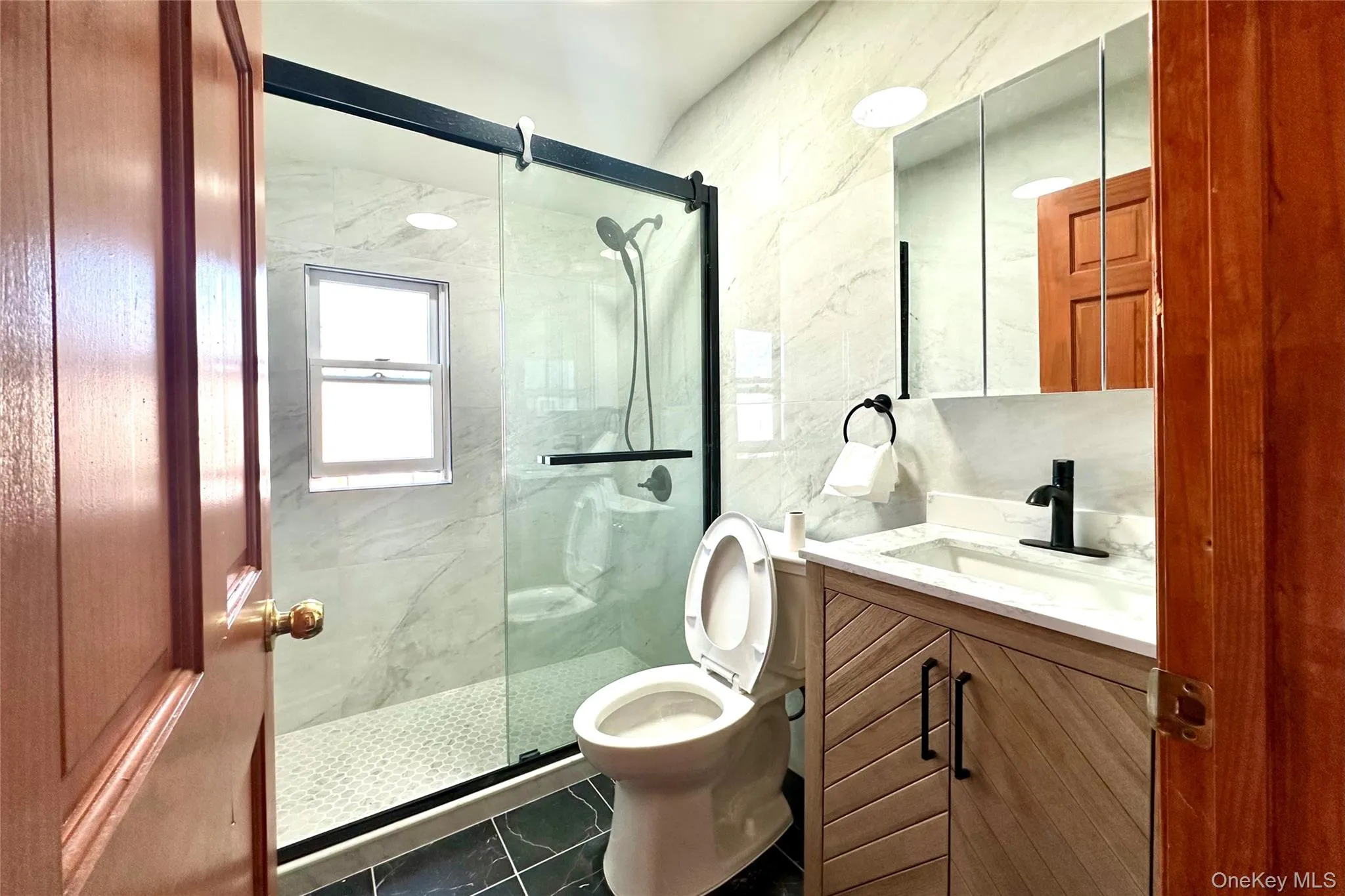 Full bath with vanity, a marble finish shower, and tile walls Full bath with vanity, a marble finish shower, and tile walls