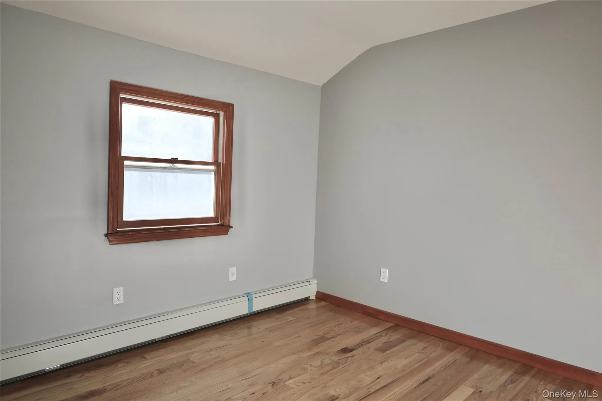Unfurnished room featuring a baseboard radiator, light wood-style floors, and lofted ceiling Unfurnished room featuring a baseboard radiator, light wood-style floors, and lofted ceiling