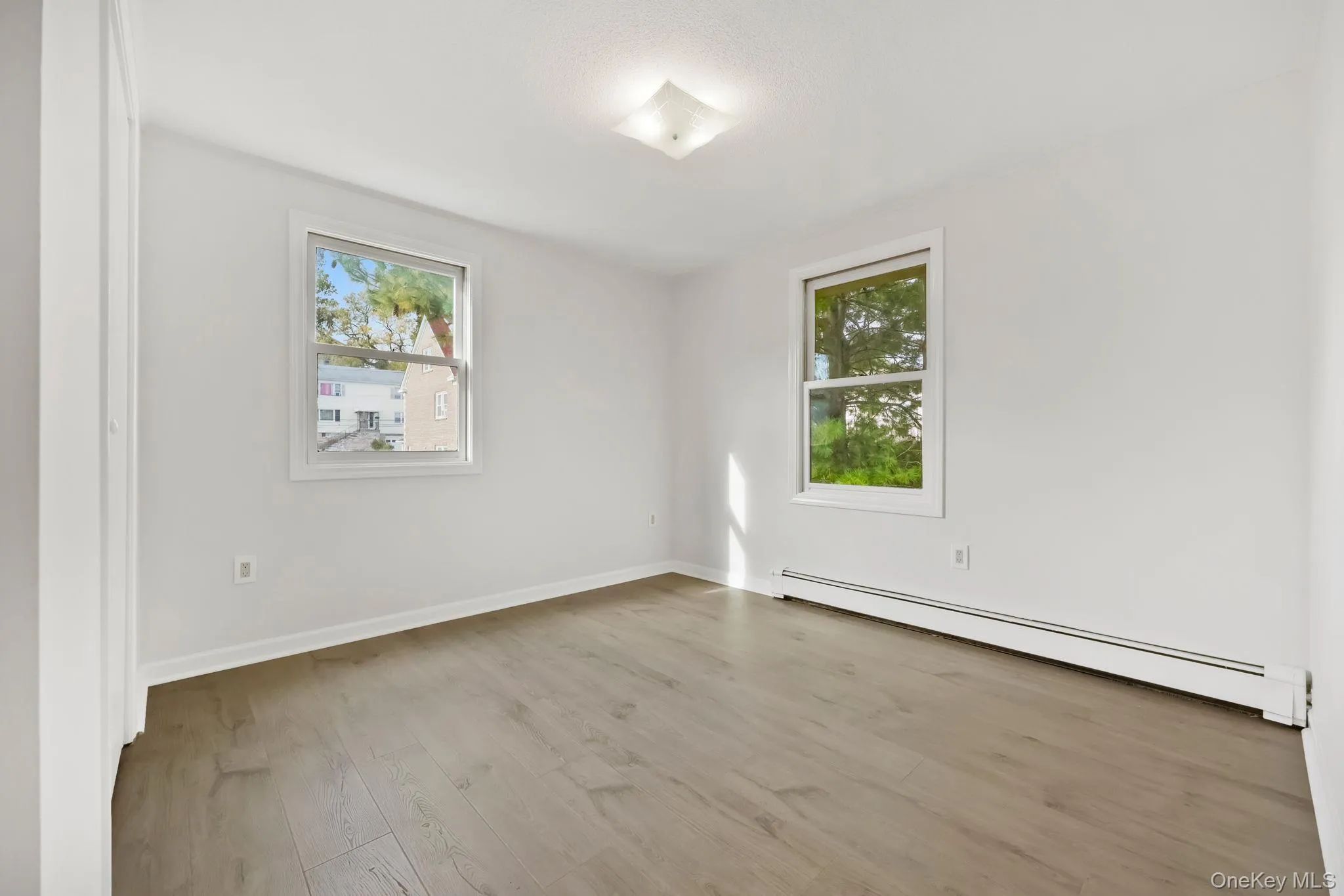 Empty room featuring baseboard heating and light wood-style floors Empty room featuring baseboard heating and light wood-style floors
