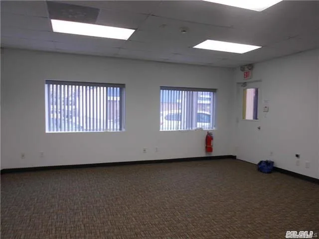 Unfurnished room featuring dark carpet and a drop ceiling Unfurnished room featuring dark carpet and a drop ceiling