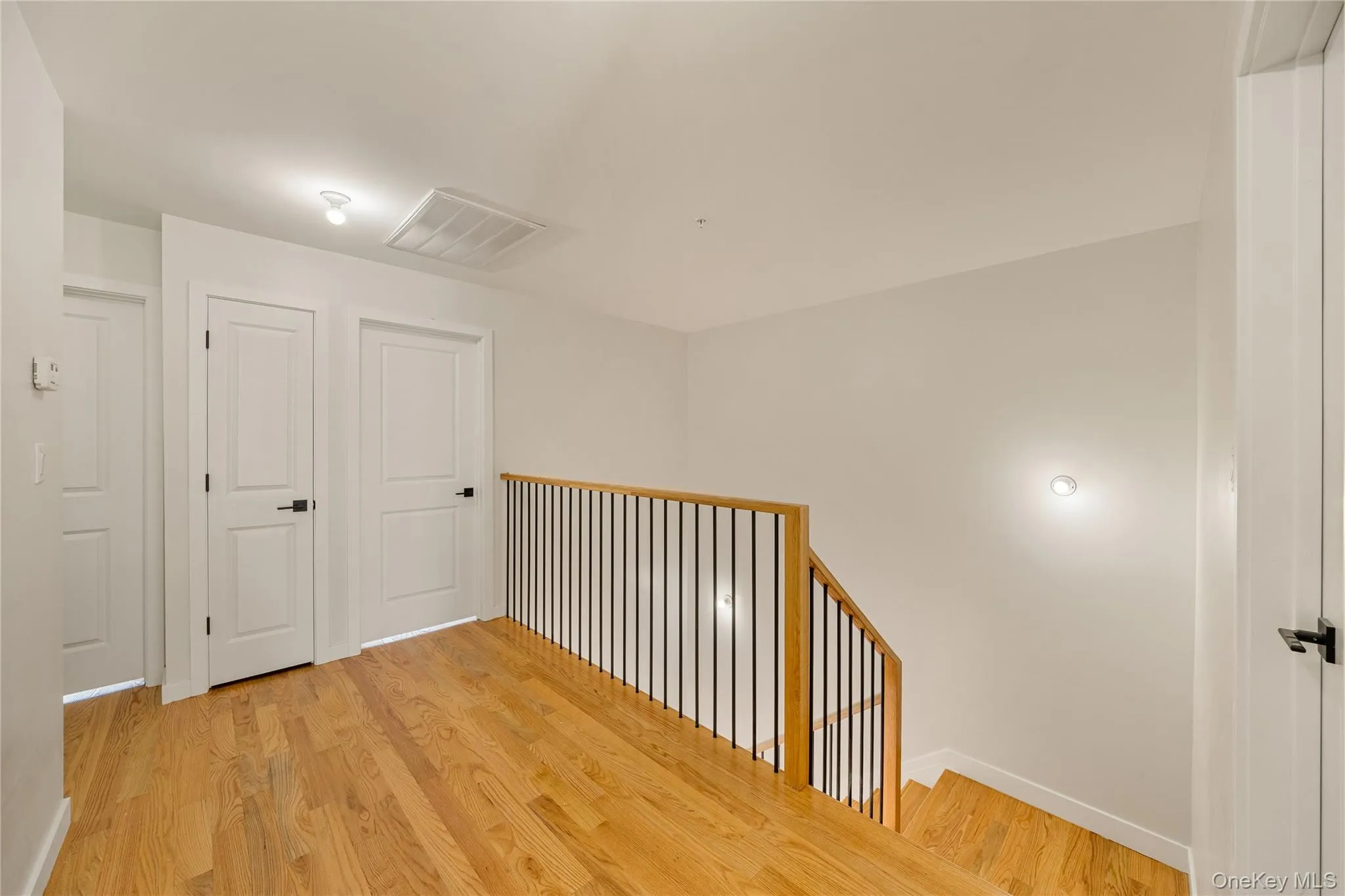 Hall featuring light wood-style floors and an upstairs landing Hall featuring light wood-style floors and an upstairs landing
