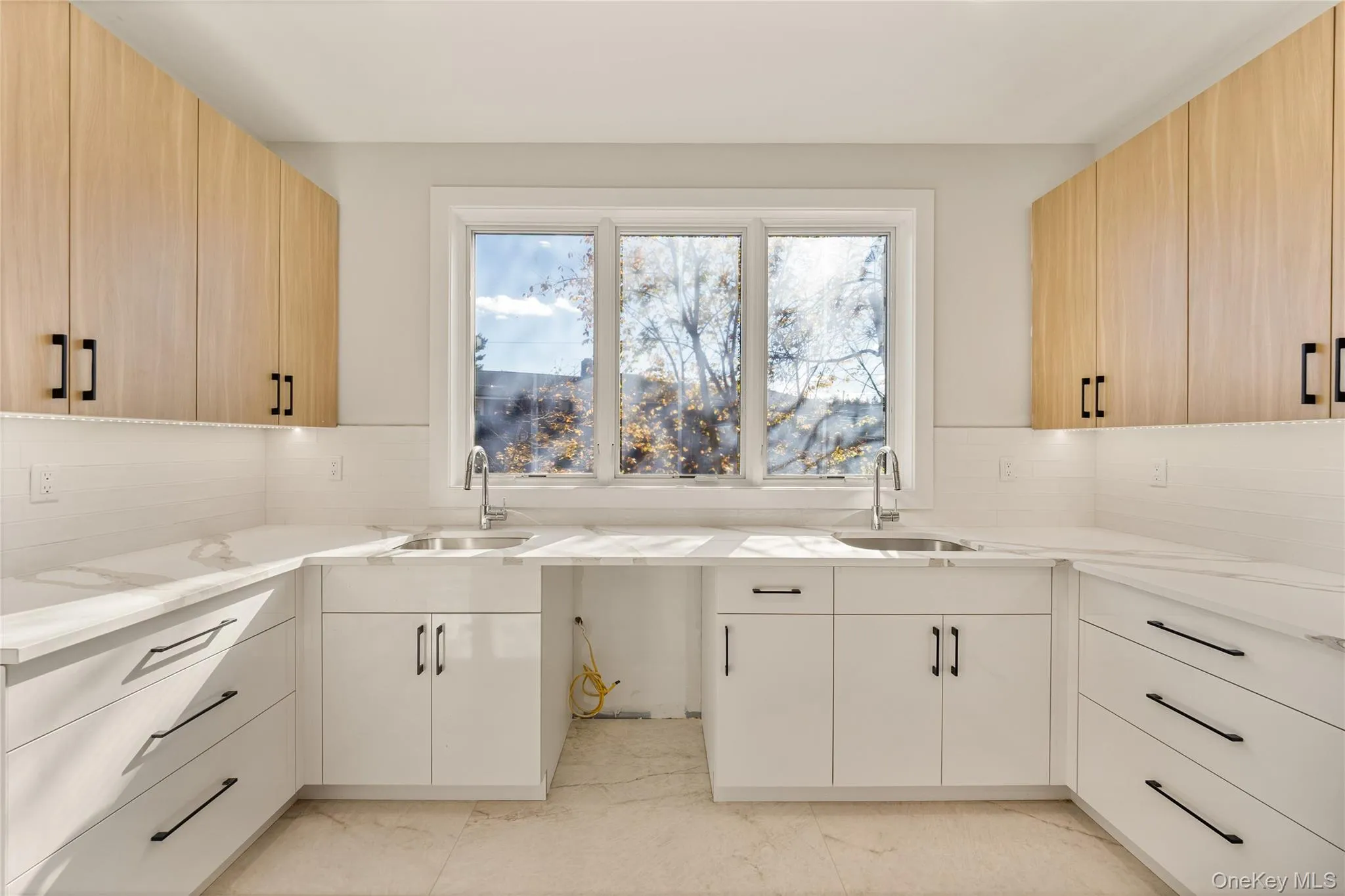 Kitchen with decorative backsplash, modern cabinets, and light stone counters Kitchen with decorative backsplash, modern cabinets, and light stone counters