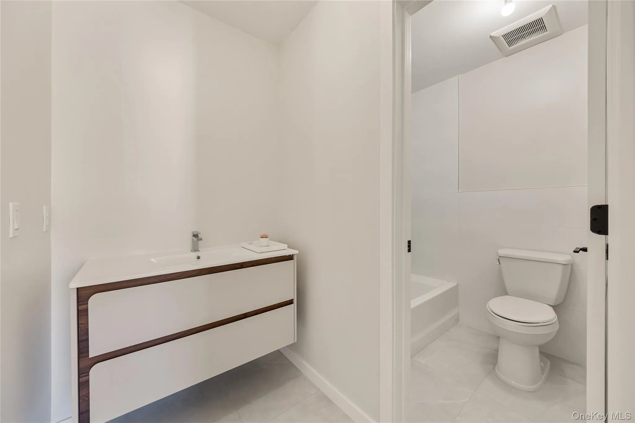 Bathroom with vanity, light tile patterned floors, and a tub Bathroom with vanity, light tile patterned floors, and a tub