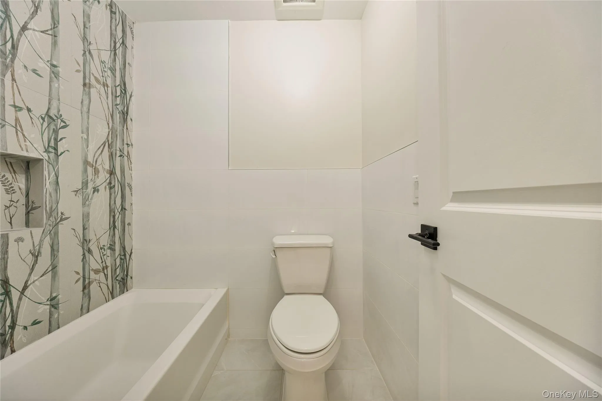 Full bathroom with tile patterned floors, tile walls, and shower / bath combo Full bathroom with tile patterned floors, tile walls, and shower / bath combo