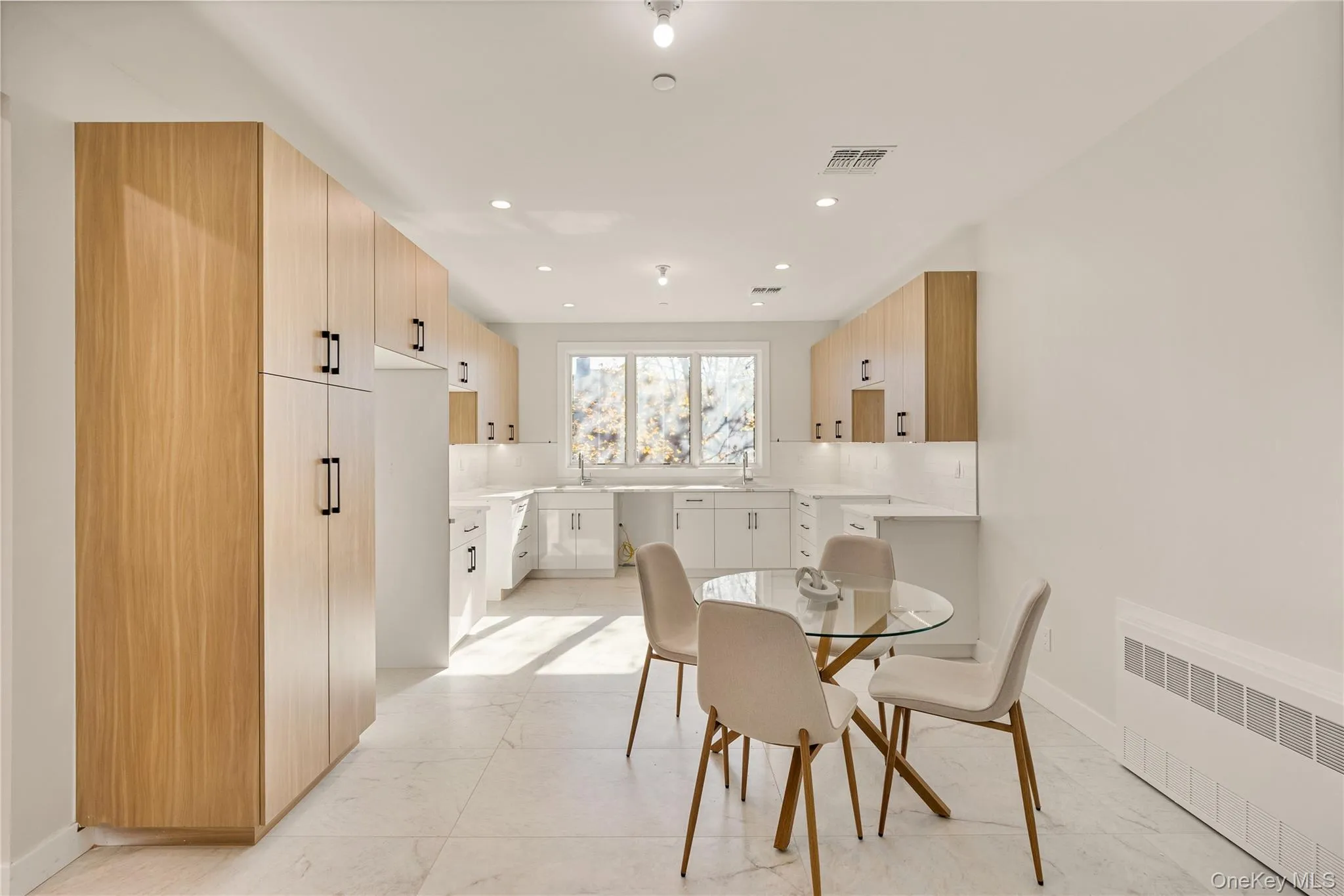 Dining space with radiator, recessed lighting, and light marble finish flooring Dining space with radiator, recessed lighting, and light marble finish flooring