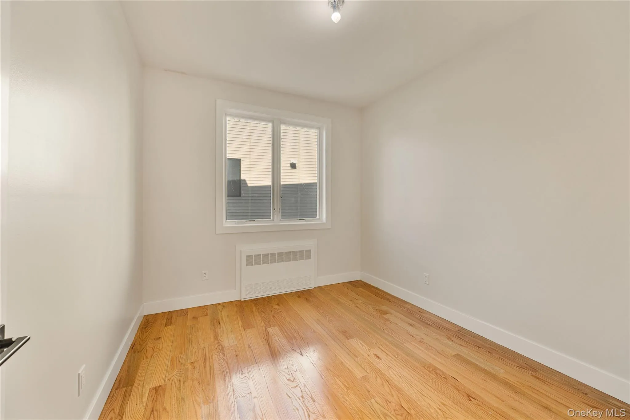 Spare room with light wood-type flooring and radiator heating unit Spare room with light wood-type flooring and radiator heating unit