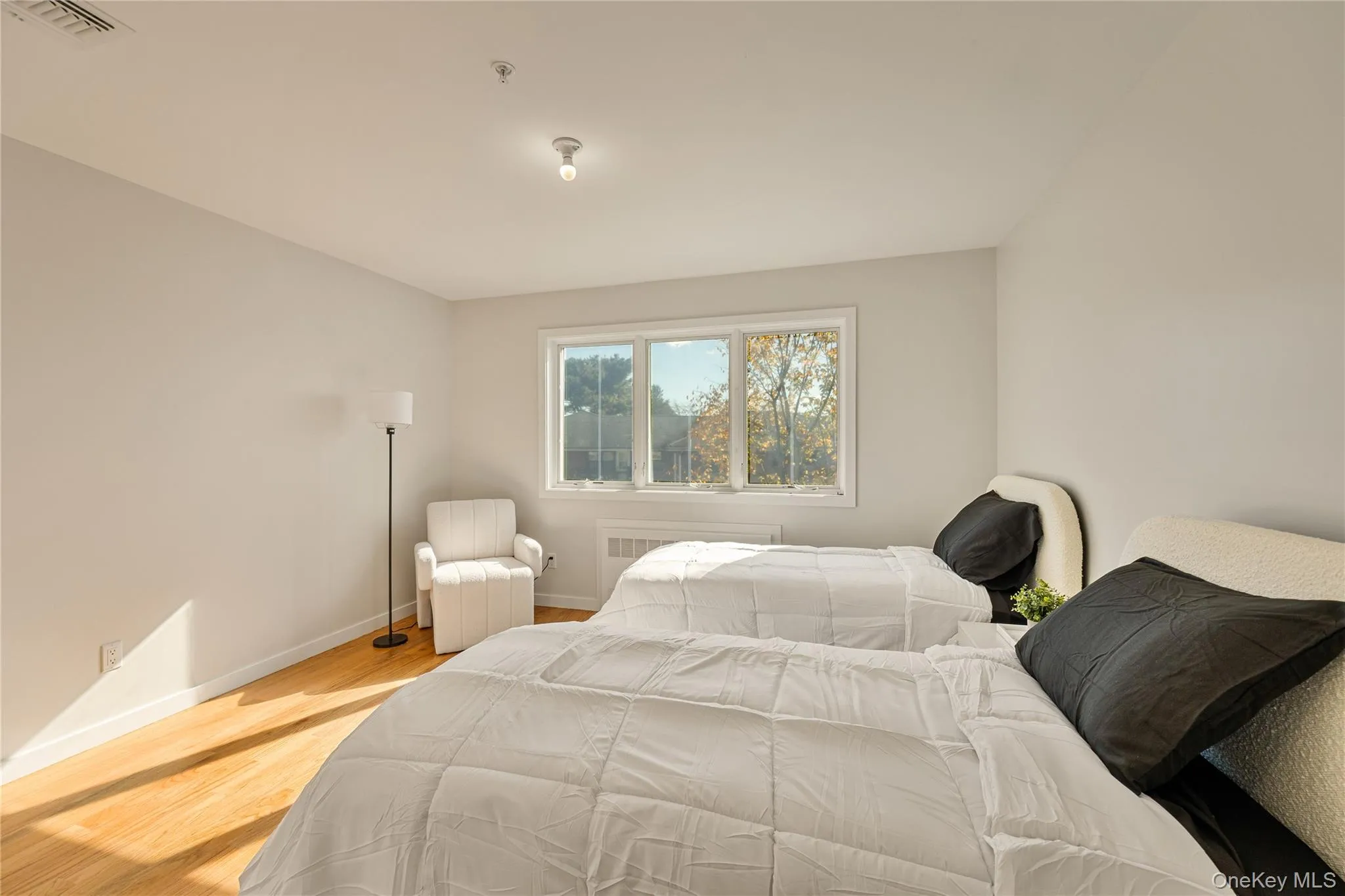 Bedroom featuring light wood-type flooring and radiator heating unit Bedroom featuring light wood-type flooring and radiator heating unit