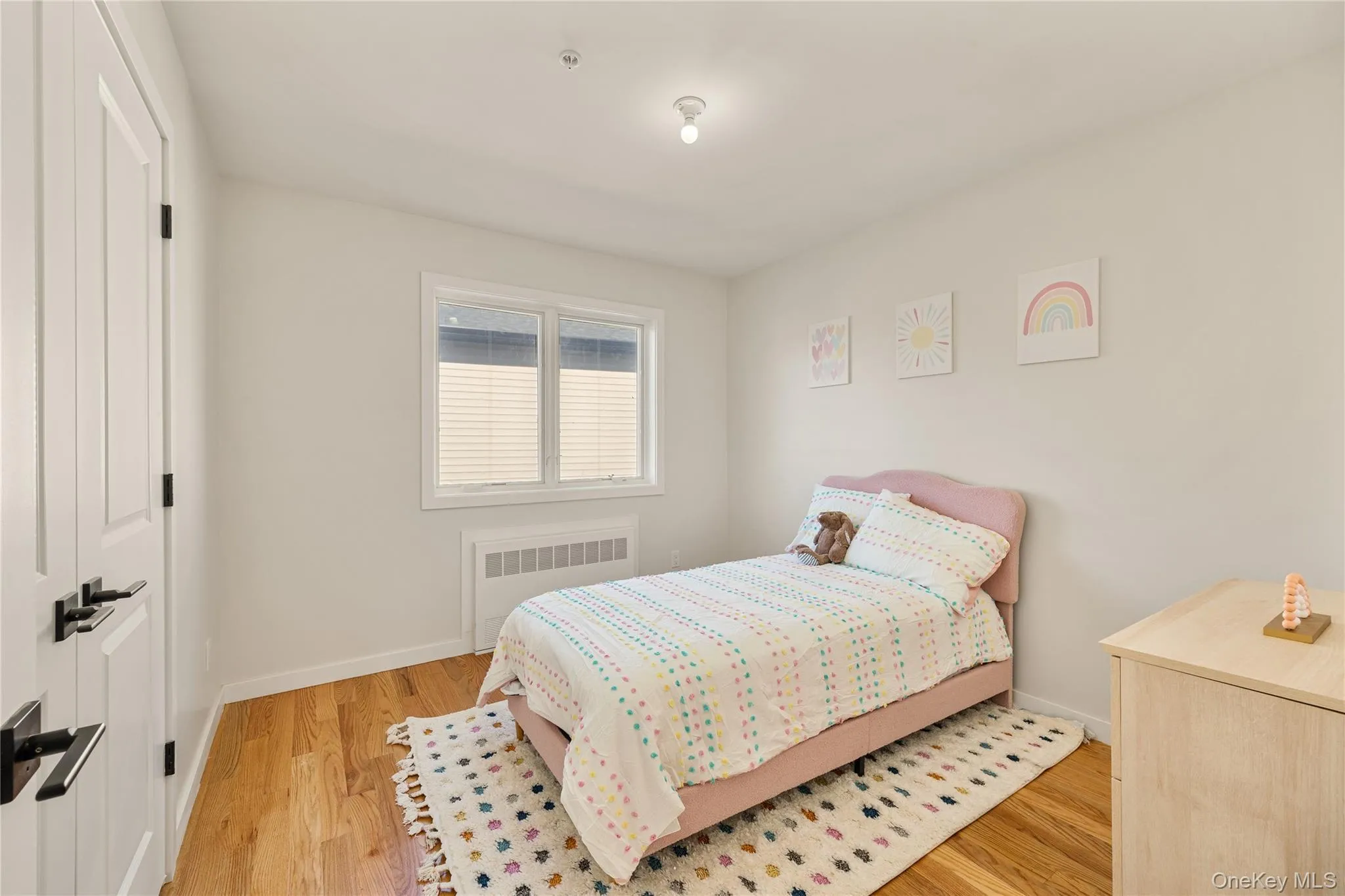 Bedroom with light wood-style floors, radiator, and a closet Bedroom with light wood-style floors, radiator, and a closet