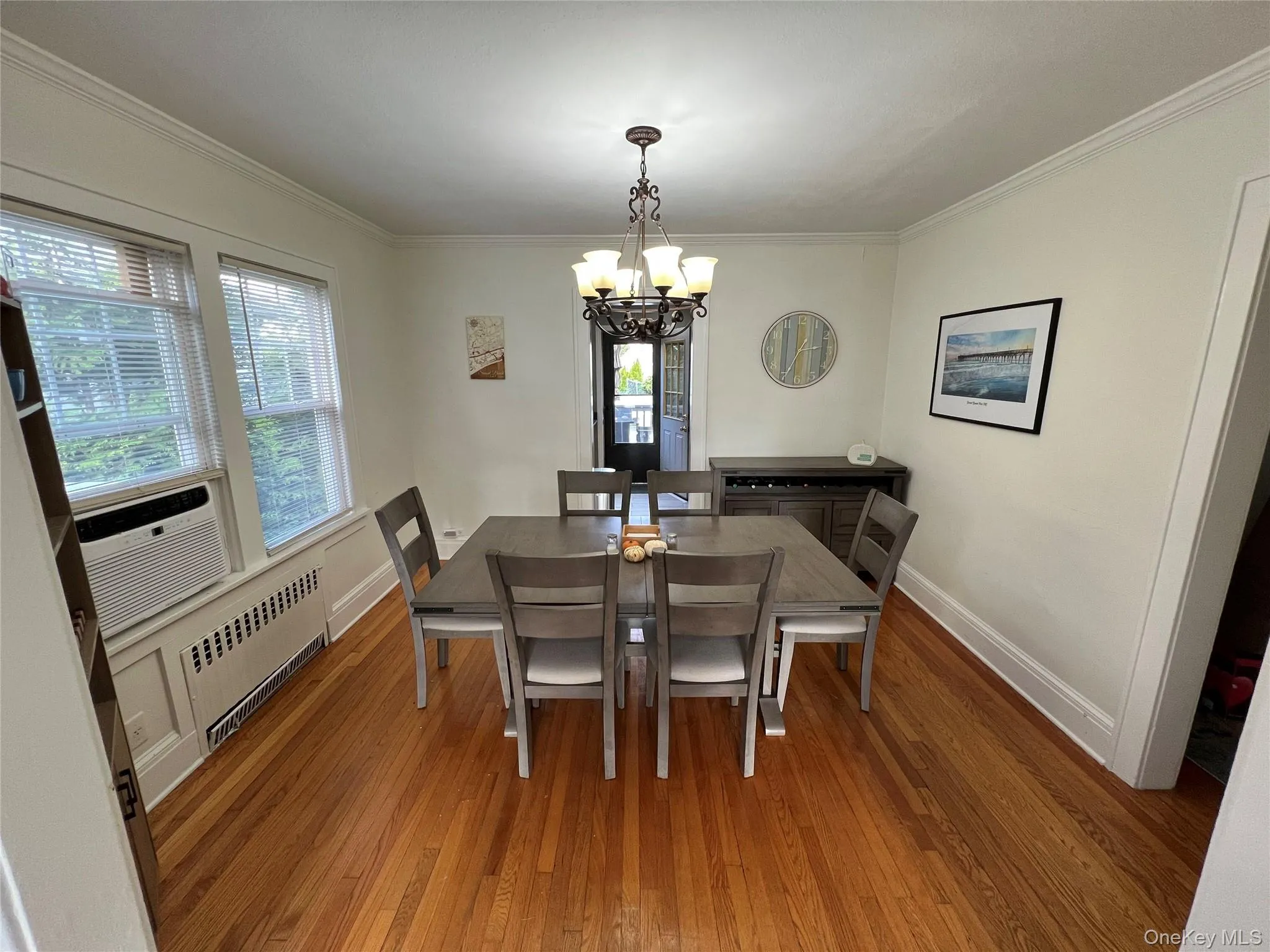 Dining room featuring hardwood / wood-style floors, crown molding, radiator heating unit, a chandelier, and cooling unit Dining room featuring hardwood / wood-style floors, crown molding, radiator heating unit, a chandelier, and cooling unit