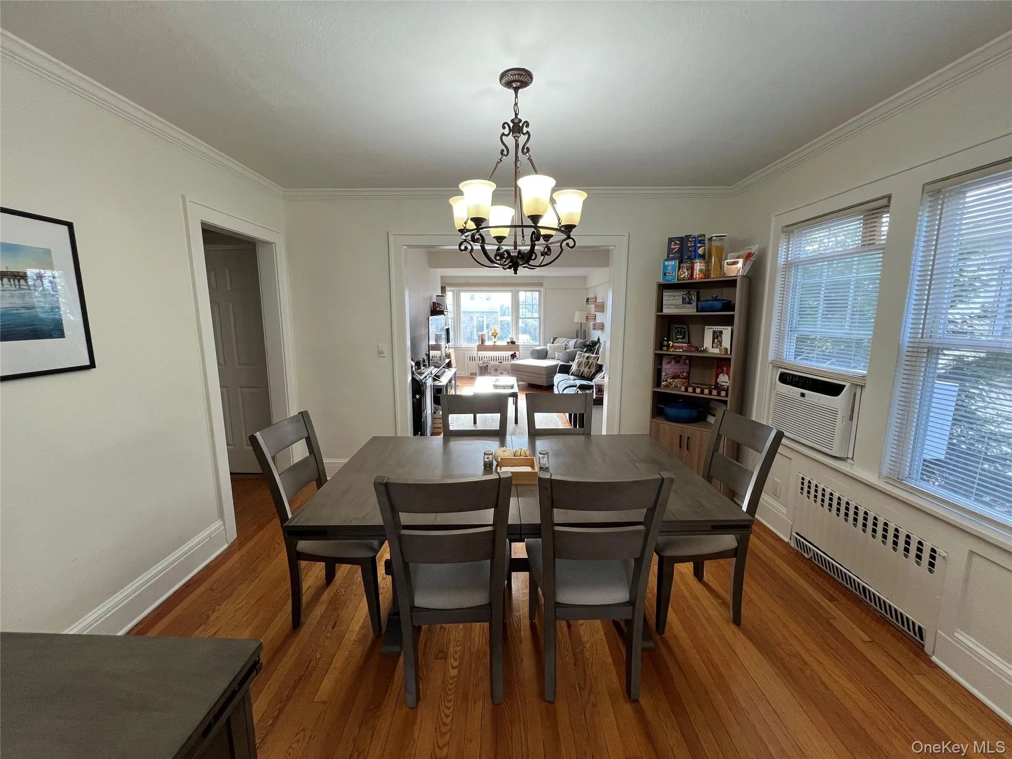 Dining room with wood finished floors, radiator, crown molding, a chandelier, and cooling unit Dining room with wood finished floors, radiator, crown molding, a chandelier, and cooling unit
