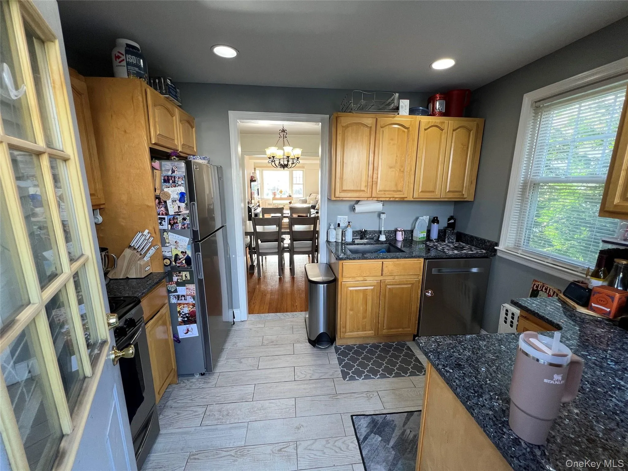 Kitchen with wood tiled floors, appliances with stainless steel finishes, dark stone counters, a chandelier, and recessed lighting Kitchen with wood tiled floors, appliances with stainless steel finishes, dark stone counters, a chandelier, and recessed lighting