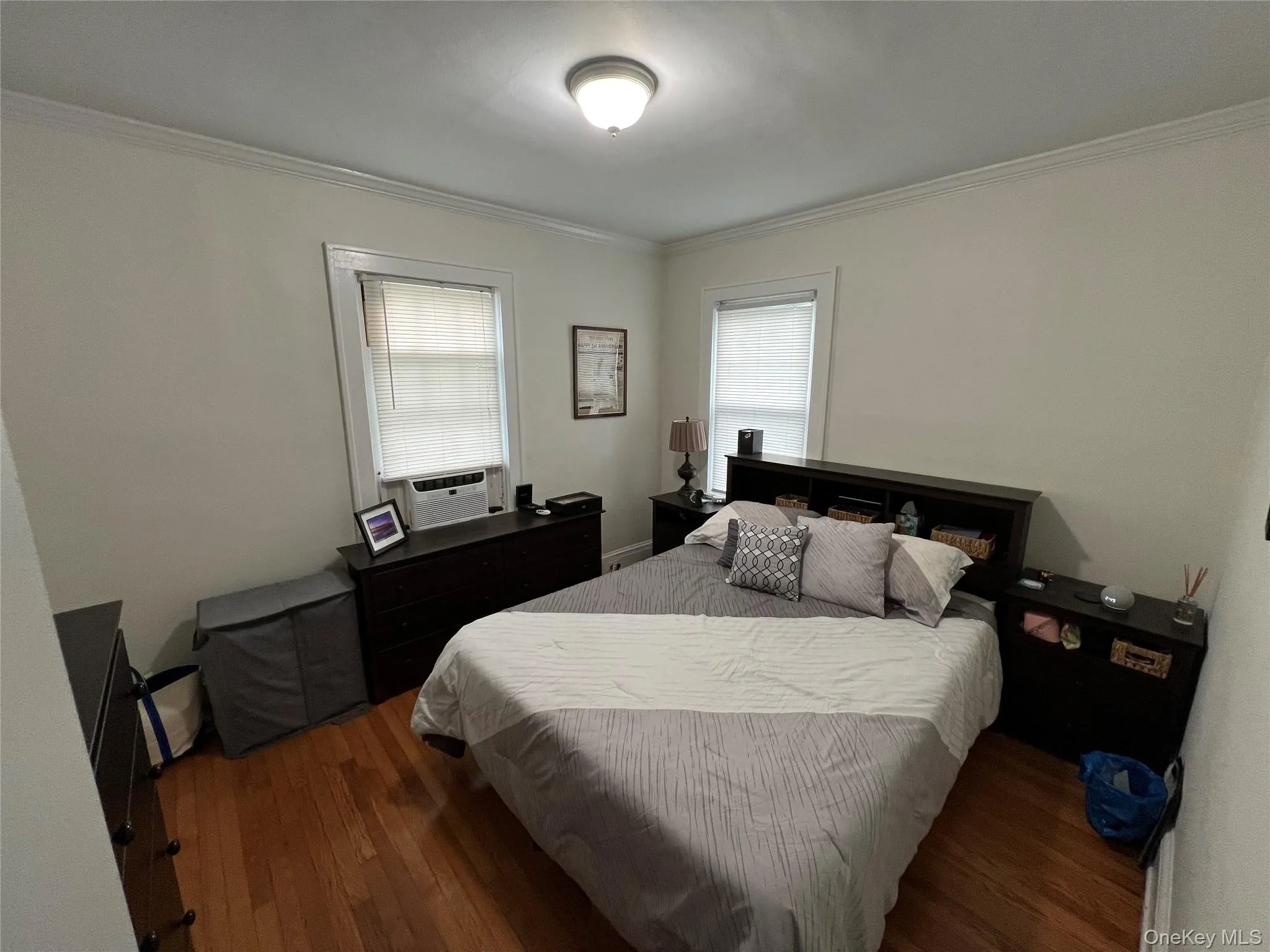 Bedroom with ornamental molding, hardwood / wood-style flooring, and cooling unit Bedroom with ornamental molding, hardwood / wood-style flooring, and cooling unit