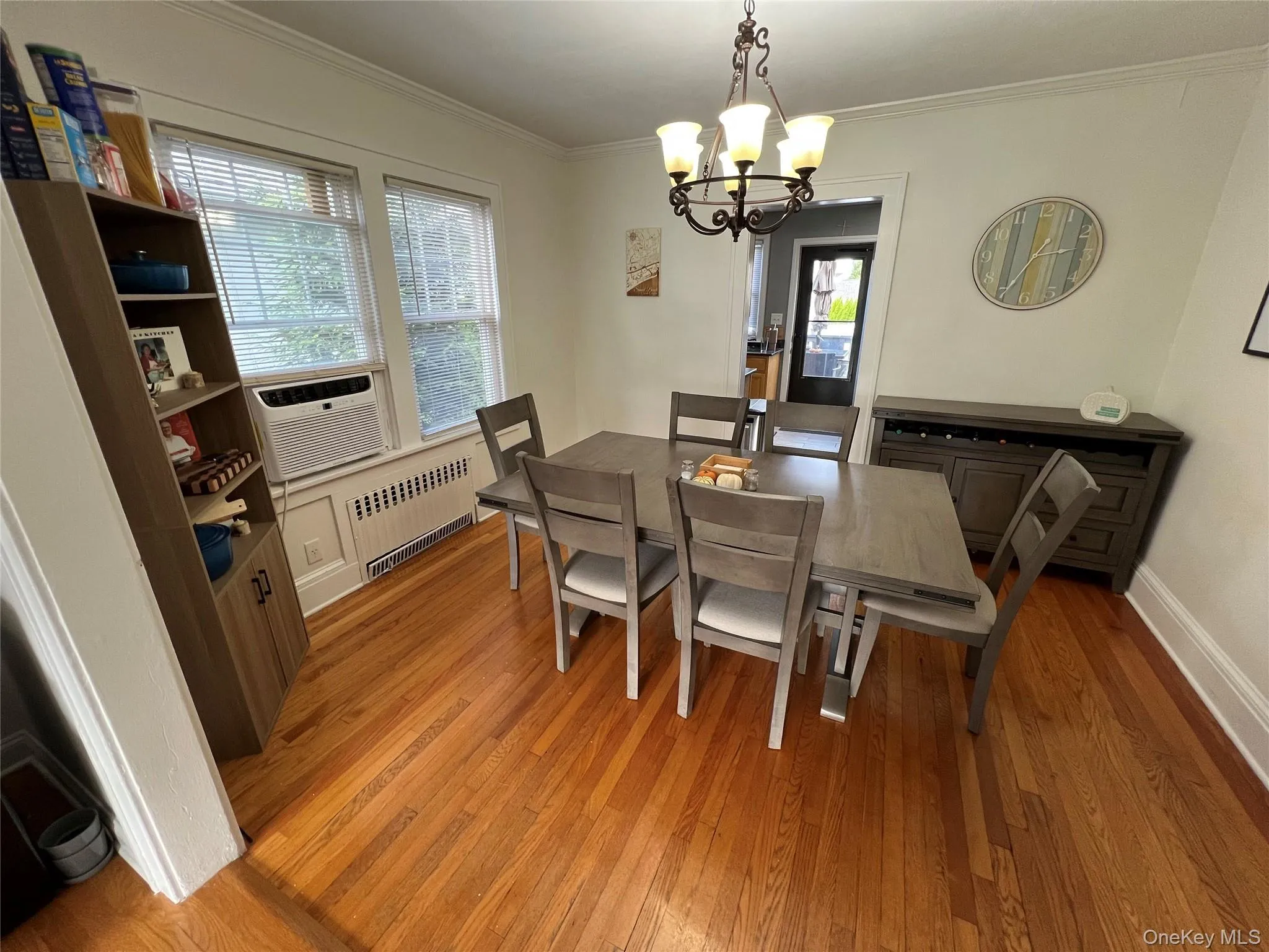 Dining area featuring light wood-style flooring, ornamental molding, radiator, cooling unit, and a chandelier Dining area featuring light wood-style flooring, ornamental molding, radiator, cooling unit, and a chandelier