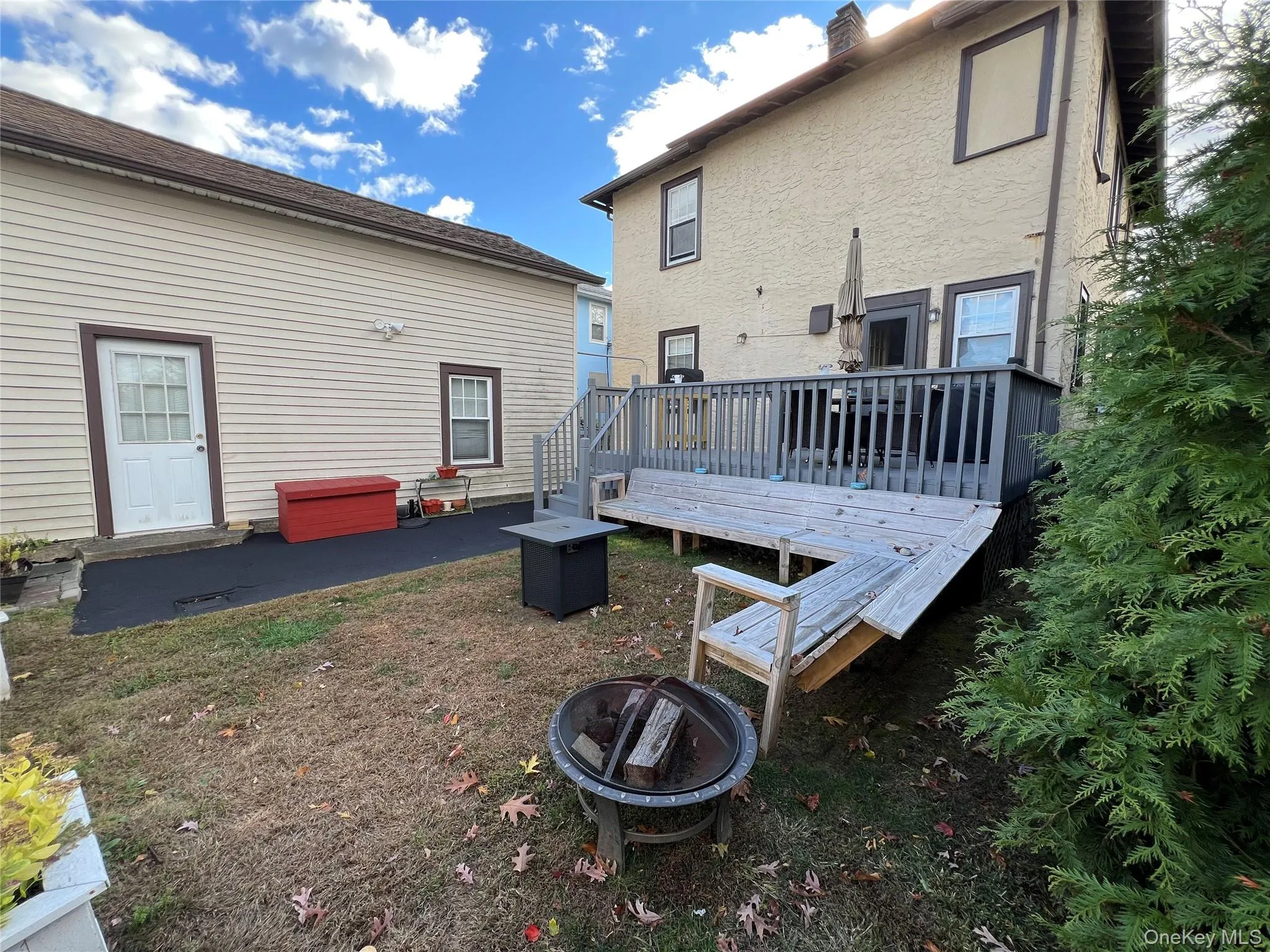 Back of property featuring a patio, stucco siding, a deck, an outdoor fire pit, and a chimney Back of property featuring a patio, stucco siding, a deck, an outdoor fire pit, and a chimney