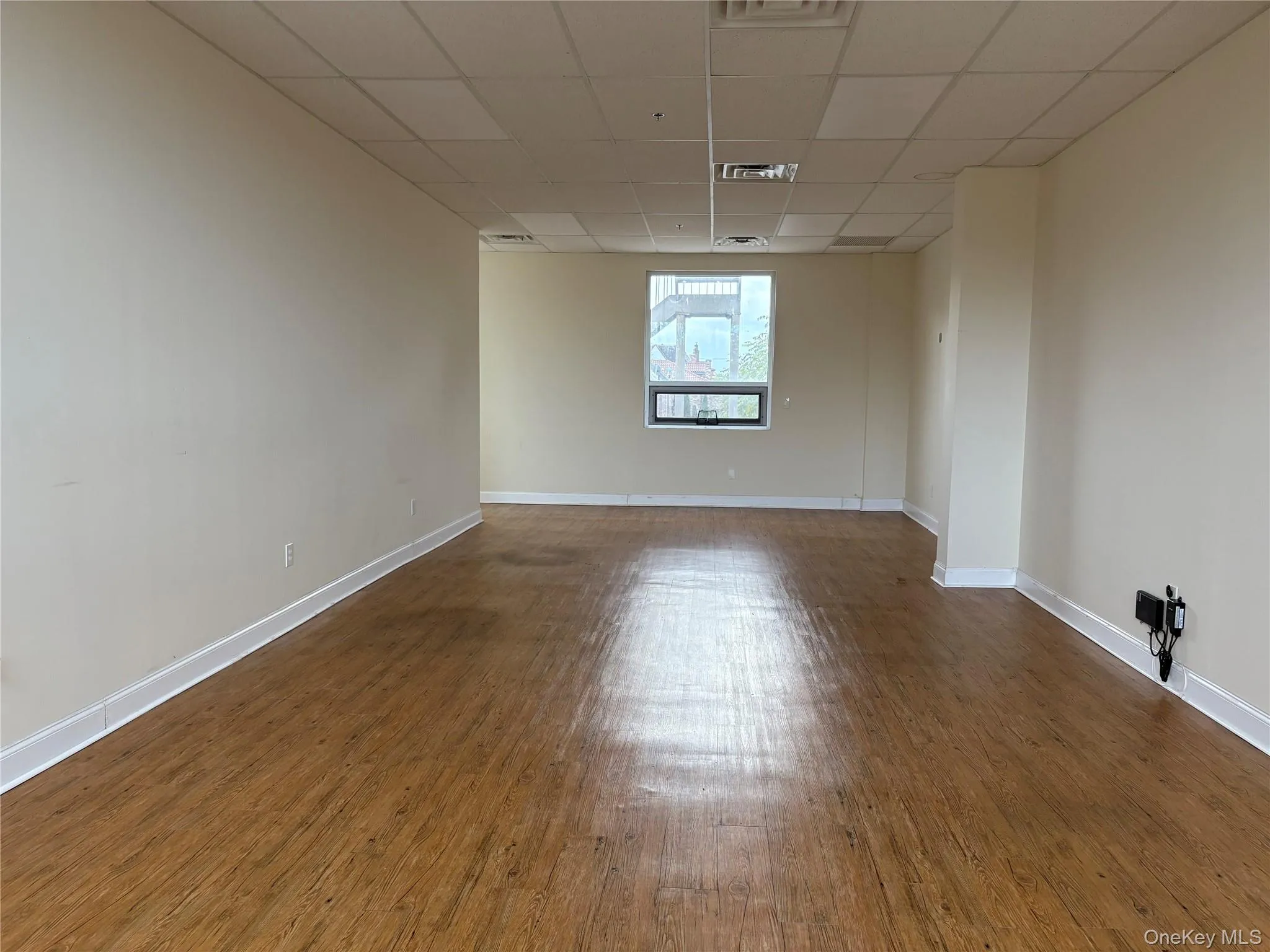 Spare room featuring a drop ceiling and dark wood-style flooring Spare room featuring a drop ceiling and dark wood-style flooring