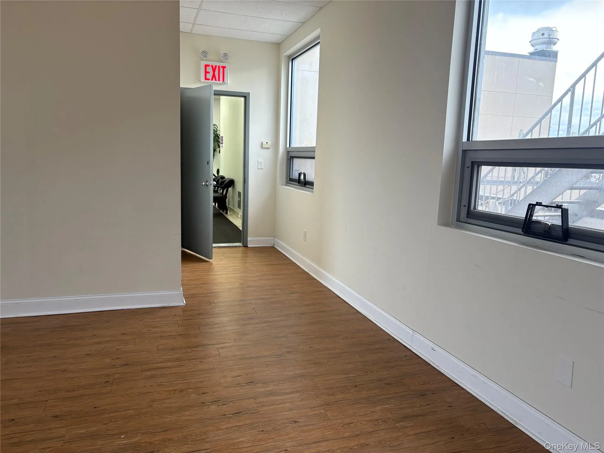 Hallway featuring dark wood finished floors and a drop ceiling Hallway featuring dark wood finished floors and a drop ceiling