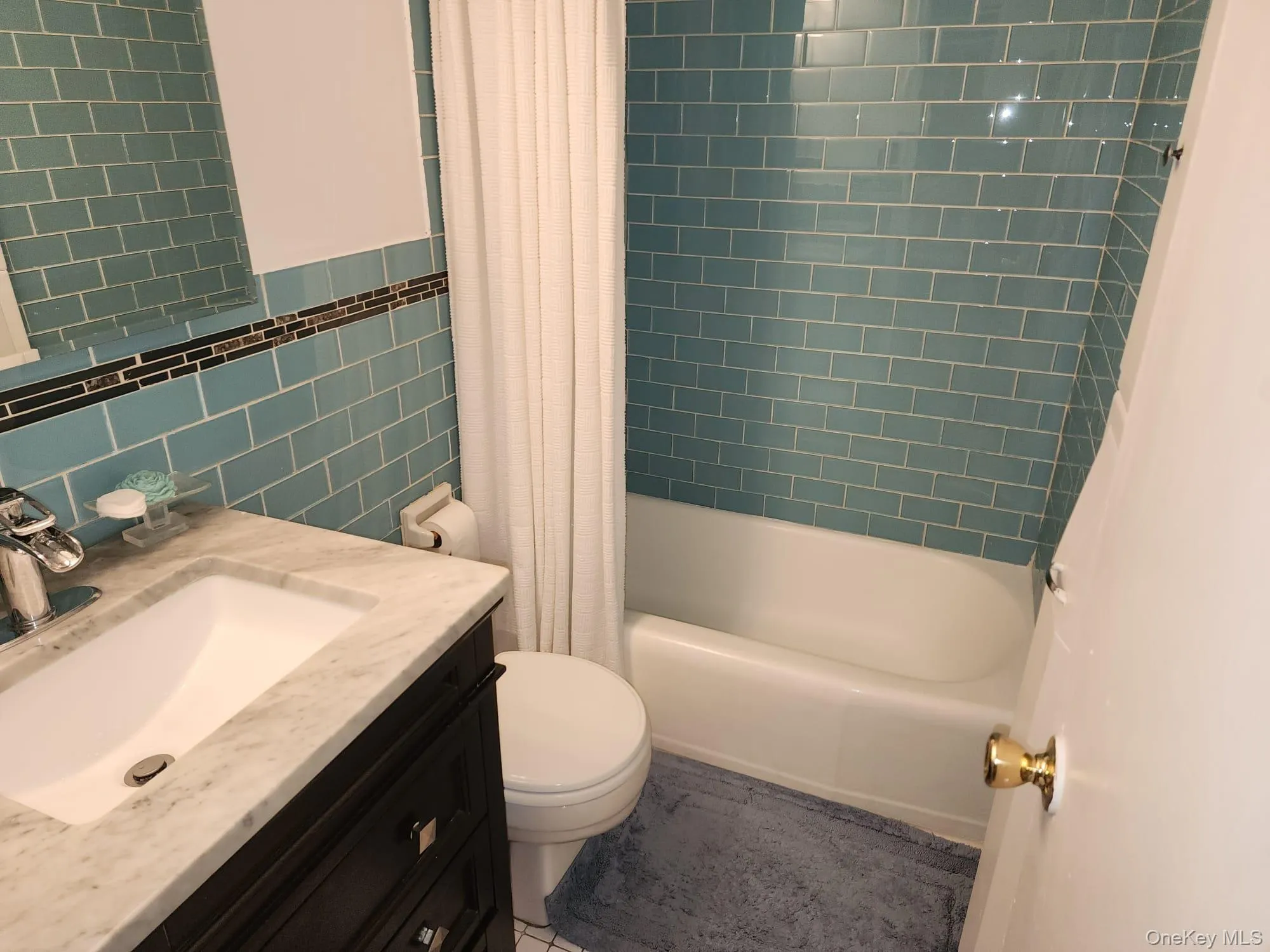 Full bath with tile walls, vanity, shower / tub combo with curtain, and light tile patterned floors Full bath with tile walls, vanity, shower / tub combo with curtain, and light tile patterned floors
