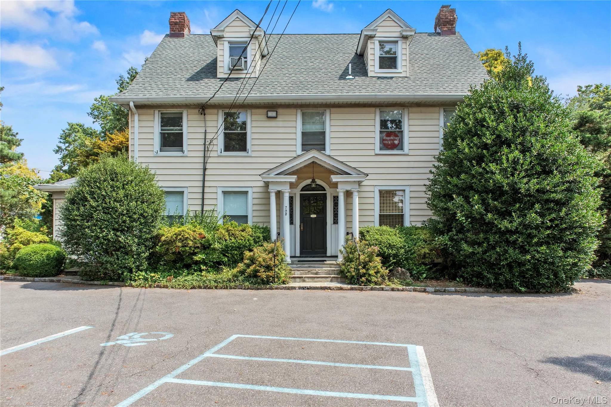 Colonial house with a chimney, roof with shingles, and uncovered parking Colonial house with a chimney, roof with shingles, and uncovered parking