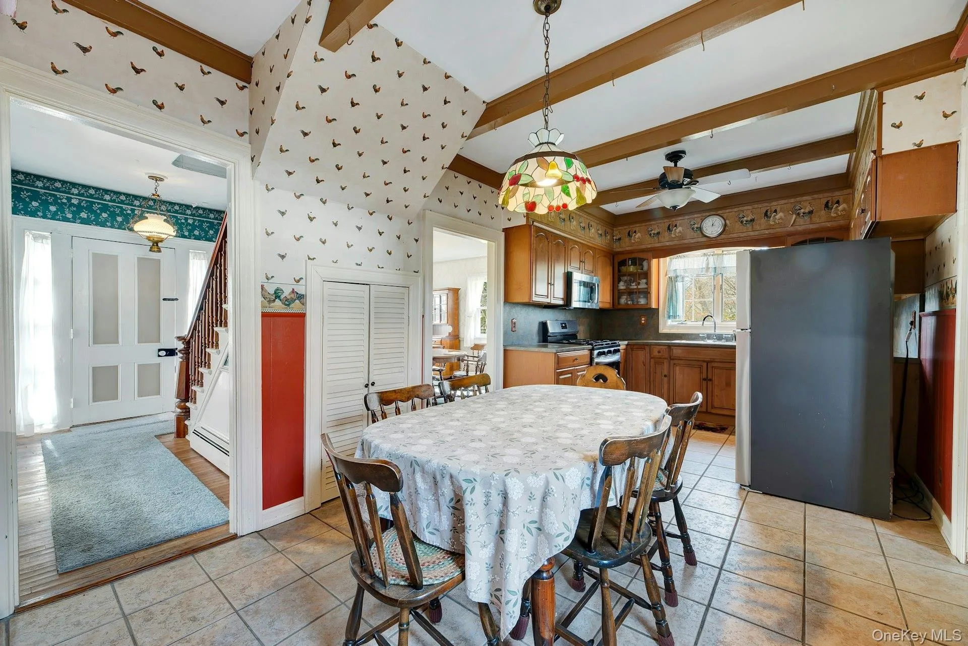 Dining room featuring wallpapered walls, a baseboard radiator, stairs, ceiling fan, and beam ceiling Dining room featuring wallpapered walls, a baseboard radiator, stairs, ceiling fan, and beam ceiling