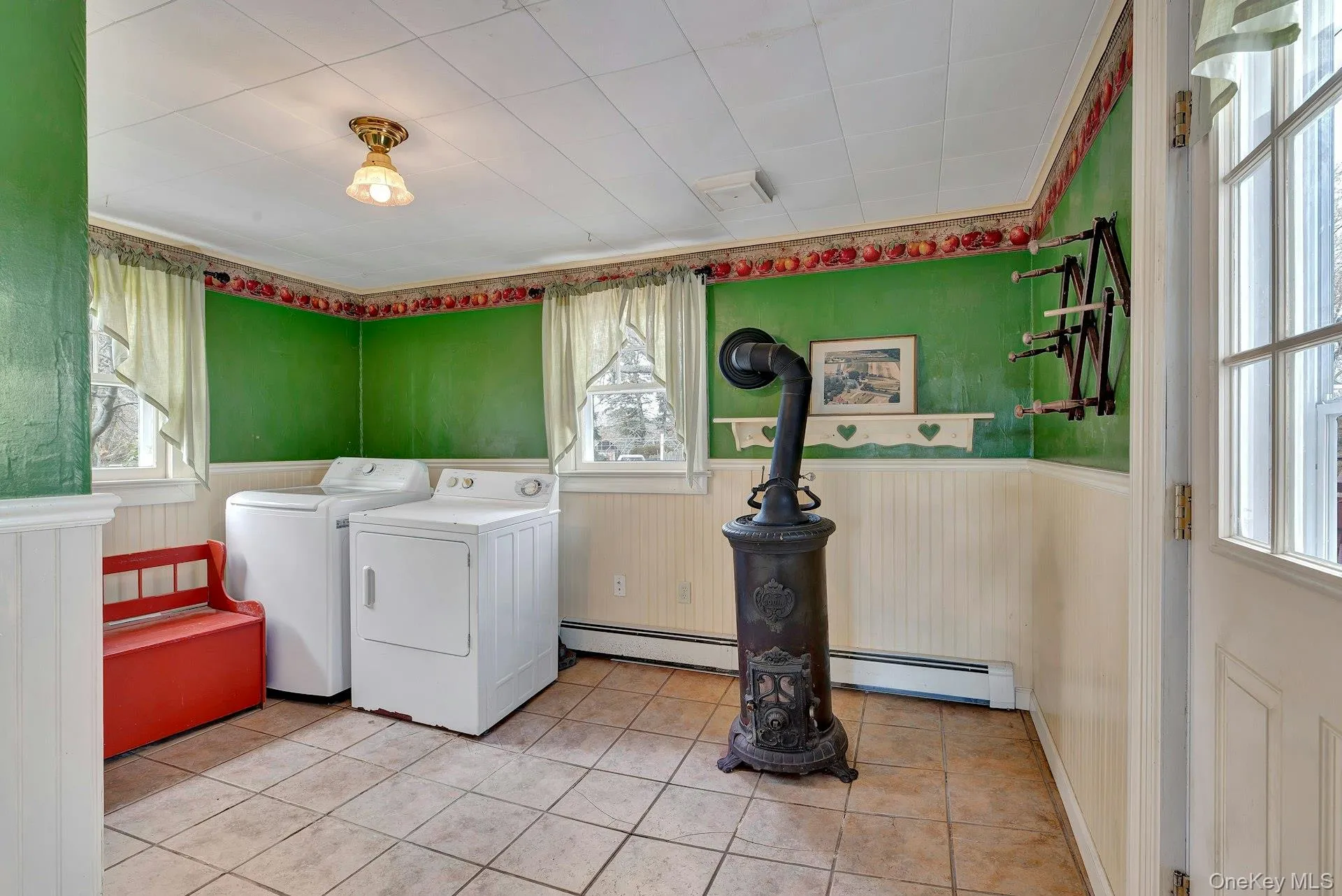 Washroom with a baseboard radiator, wainscoting, healthy amount of natural light, and washing machine and dryer Washroom with a baseboard radiator, wainscoting, healthy amount of natural light, and washing machine and dryer