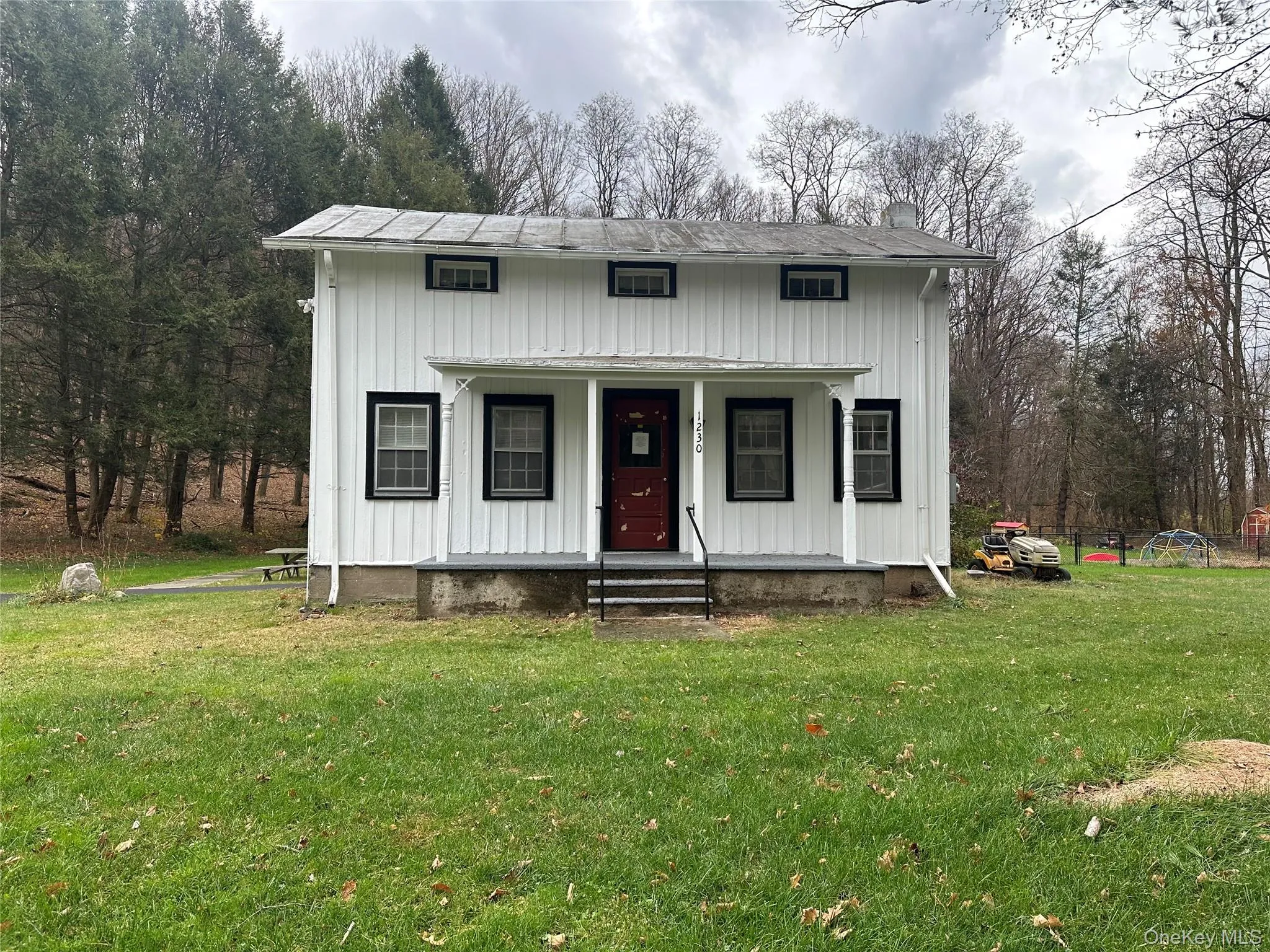 View of front of property with covered porch, a front lawn, a chimney, and board and batten siding View of front of property with covered porch, a front lawn, a chimney, and board and batten siding