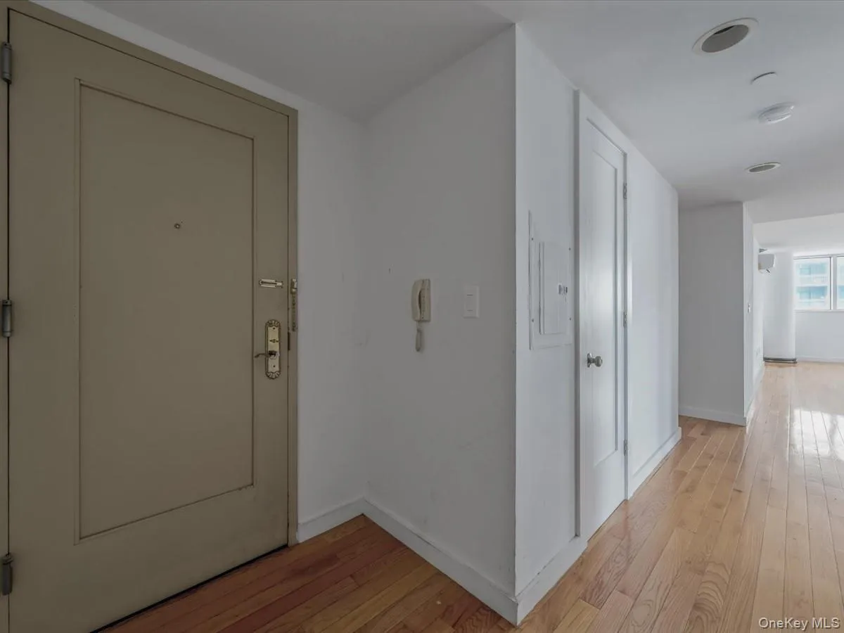 Hallway with light wood-style floors and electric panel Hallway with light wood-style floors and electric panel