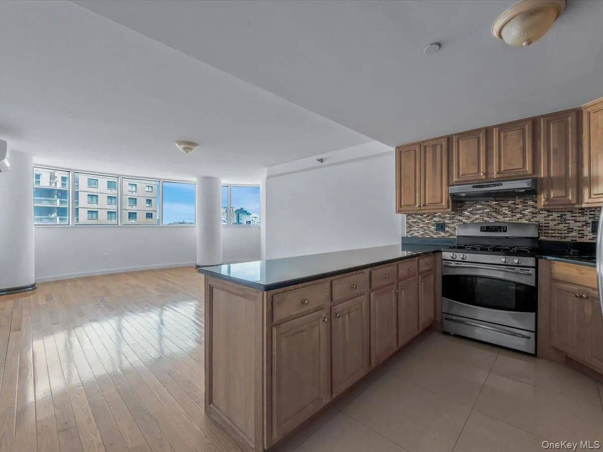 Kitchen featuring stainless steel gas range oven, tasteful backsplash, a peninsula, under cabinet range hood, and open floor plan Kitchen featuring stainless steel gas range oven, tasteful backsplash, a peninsula, under cabinet range hood, and open floor plan