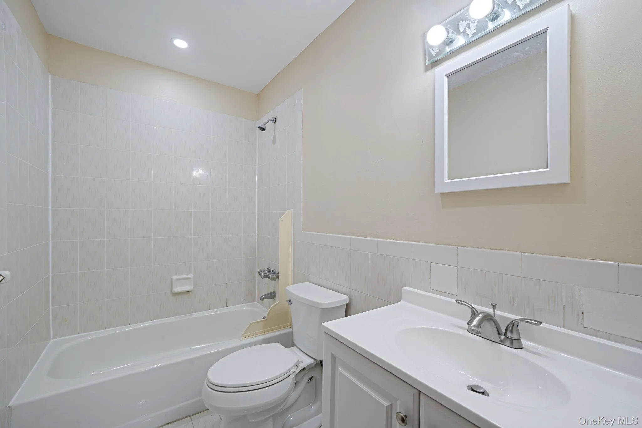 Bathroom featuring vanity, shower combination, tile walls, and recessed lighting Bathroom featuring vanity, shower combination, tile walls, and recessed lighting