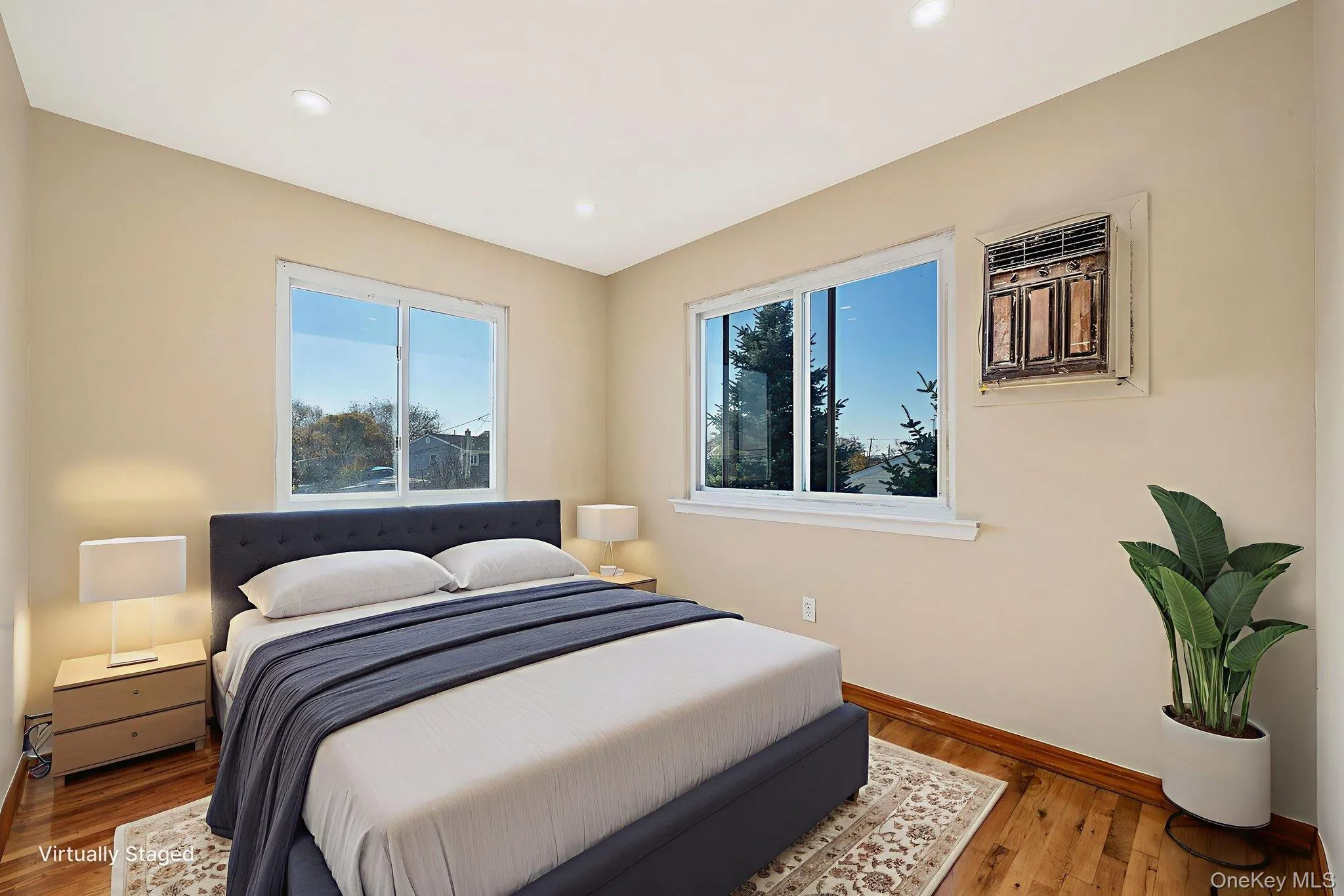 Bedroom featuring wood finished floors, multiple windows, recessed lighting, and an AC wall unit Bedroom featuring wood finished floors, multiple windows, recessed lighting, and an AC wall unit