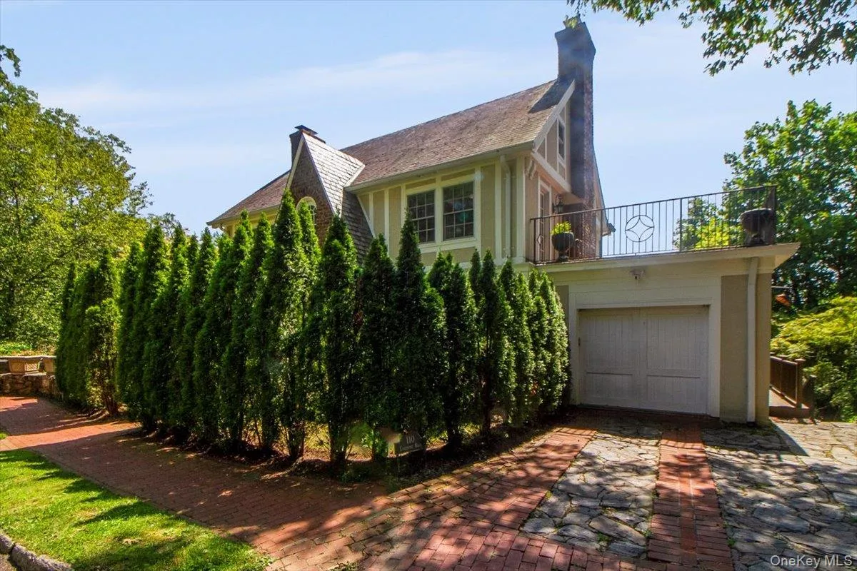 View of home's exterior with a balcony, a chimney, decorative driveway, and a garage View of home's exterior with a balcony, a chimney, decorative driveway, and a garage