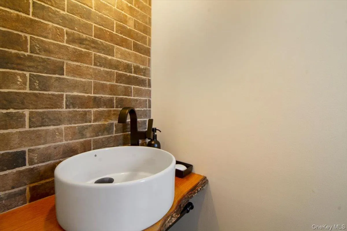 Bathroom featuring brick wall and a sink Bathroom featuring brick wall and a sink