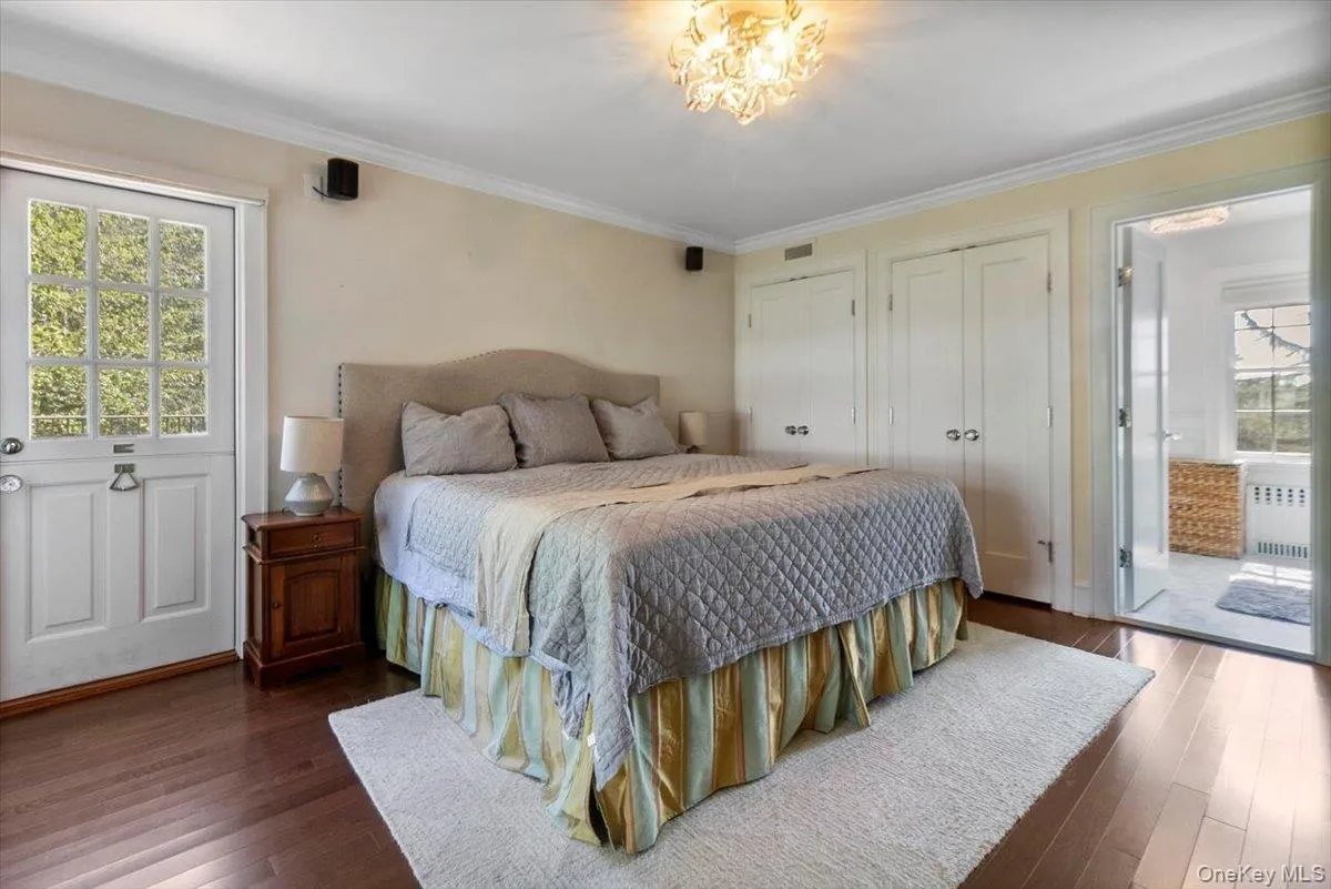 Bedroom with ornamental molding, dark wood-style flooring, radiator heating unit, and two closets Bedroom with ornamental molding, dark wood-style flooring, radiator heating unit, and two closets