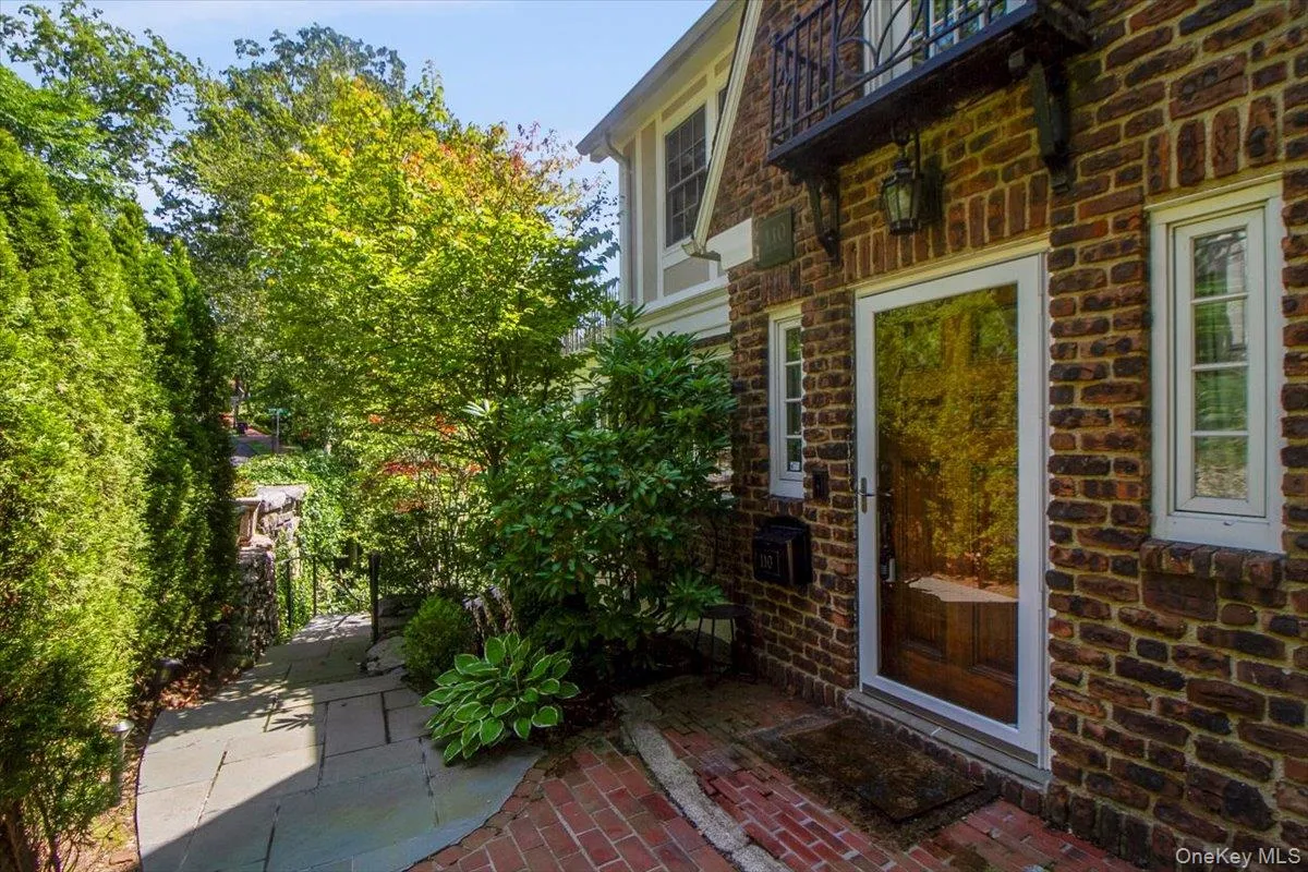 View of exterior entry with a patio area, stone siding, and a balcony View of exterior entry with a patio area, stone siding, and a balcony