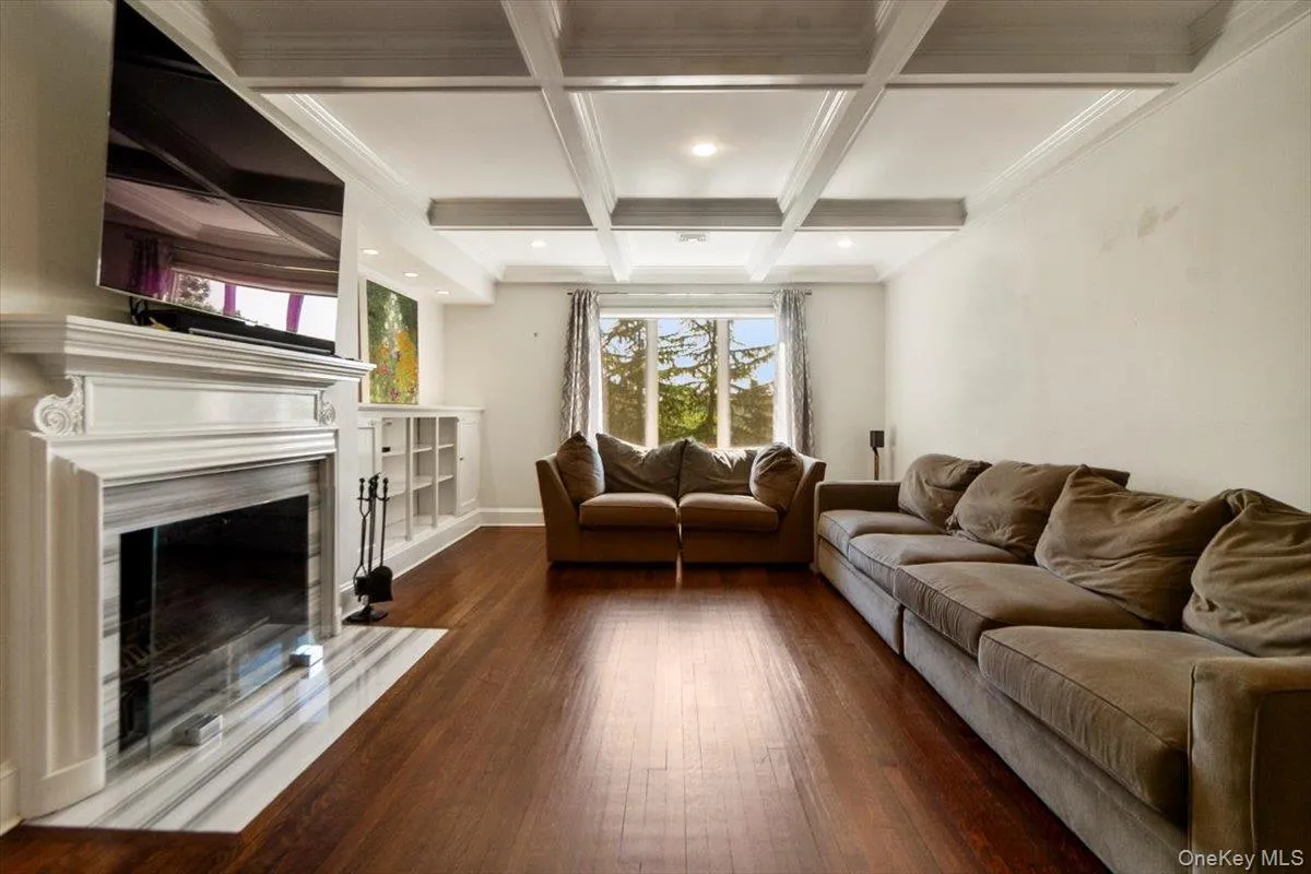 Living area featuring coffered ceiling, beamed ceiling, wood-type flooring, a premium fireplace, and recessed lighting Living area featuring coffered ceiling, beamed ceiling, wood-type flooring, a premium fireplace, and recessed lighting
