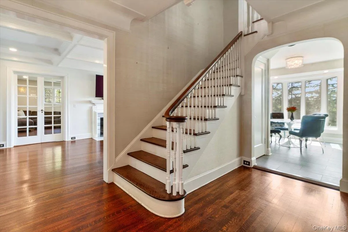 Stairs featuring arched walkways, wood finished floors, beamed ceiling, coffered ceiling, and french doors Stairs featuring arched walkways, wood finished floors, beamed ceiling, coffered ceiling, and french doors