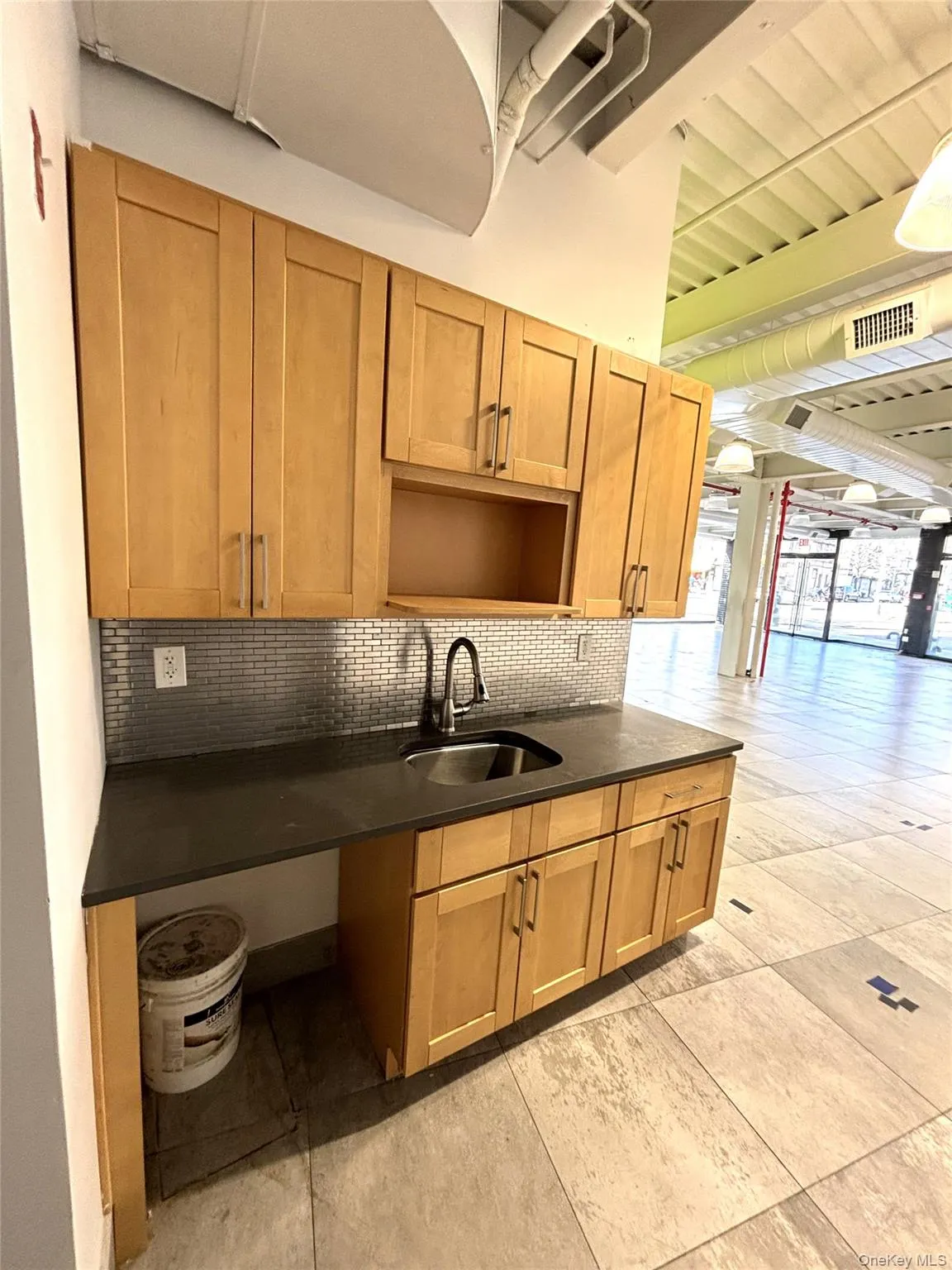 Kitchen with decorative backsplash, dark stone countertops, a wooden ceiling with exposed beams, and brown cabinets Kitchen with decorative backsplash, dark stone countertops, a wooden ceiling with exposed beams, and brown cabinets