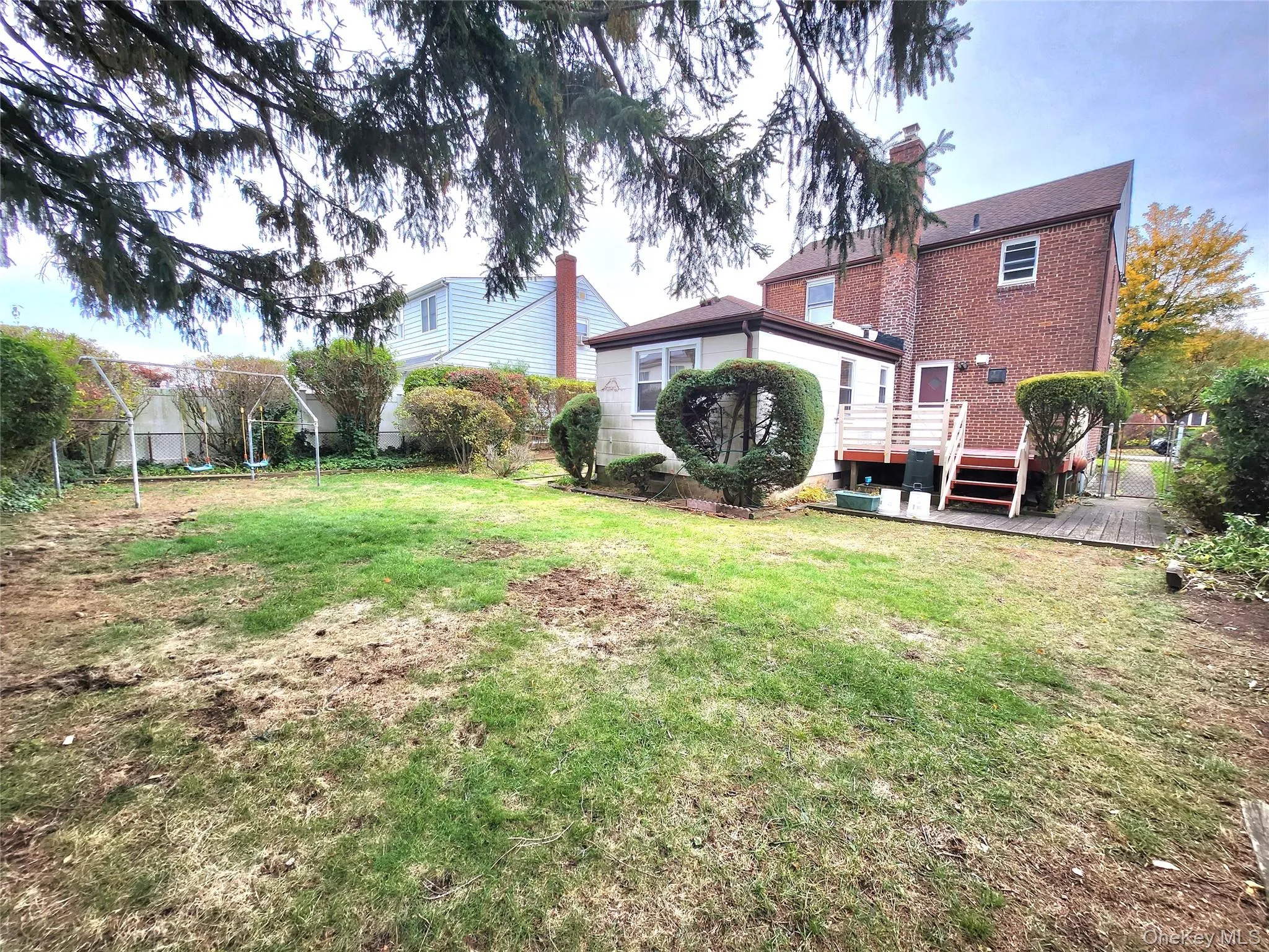 Back of house featuring a deck, a chimney, and brick siding Back of house featuring a deck, a chimney, and brick siding