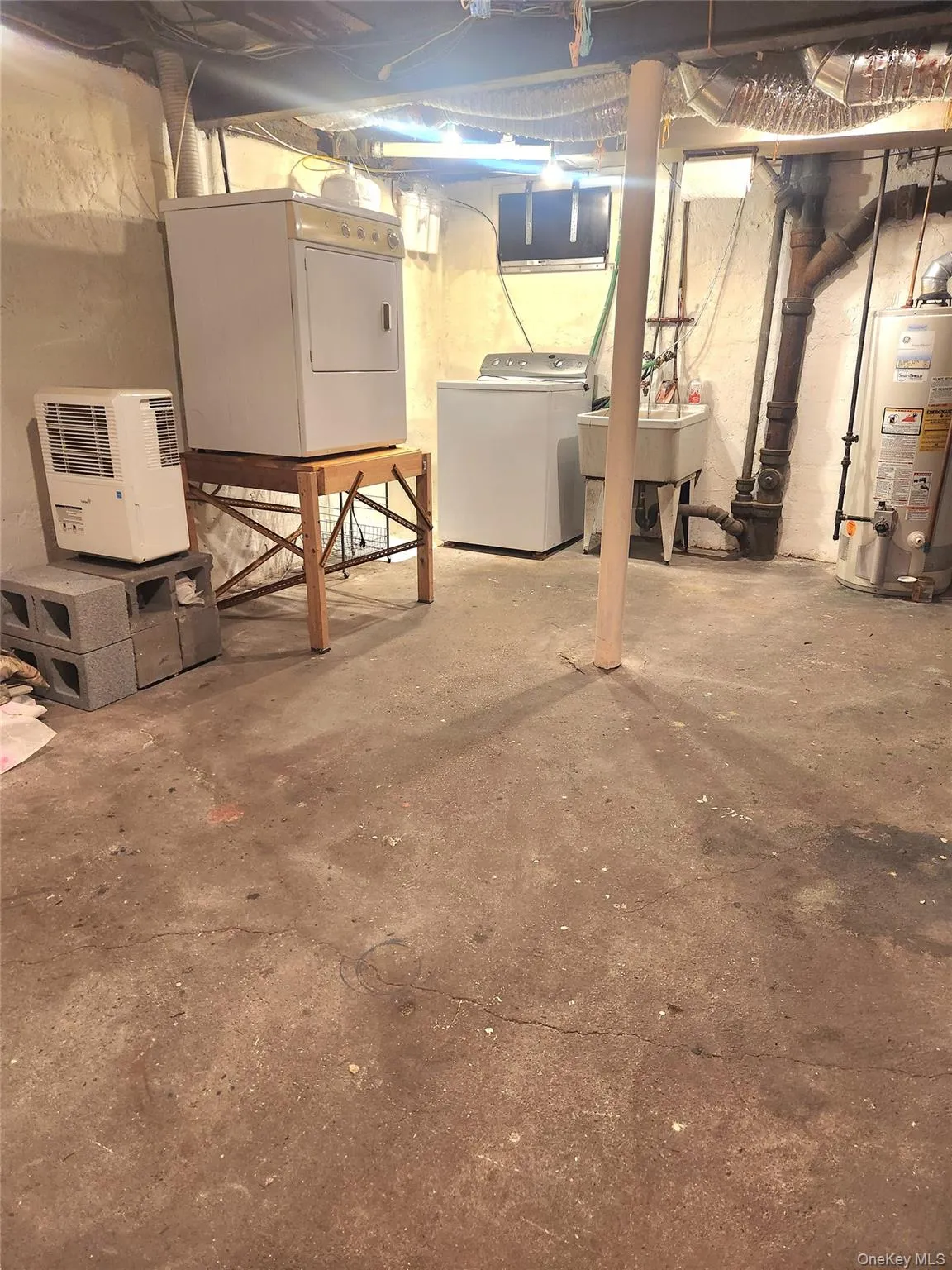 Unfinished below grade area with water heater and independent washer and dryer Unfinished below grade area with water heater and independent washer and dryer