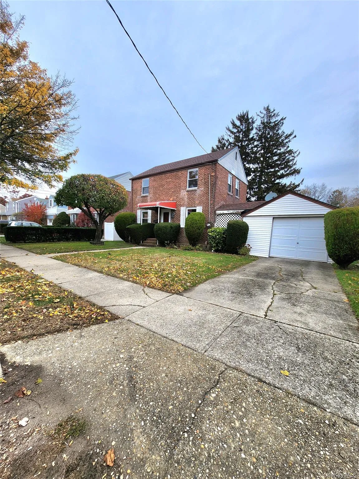 View of side of property featuring an outbuilding, a detached garage, a lawn, driveway, and brick siding View of side of property featuring an outbuilding, a detached garage, a lawn, driveway, and brick siding