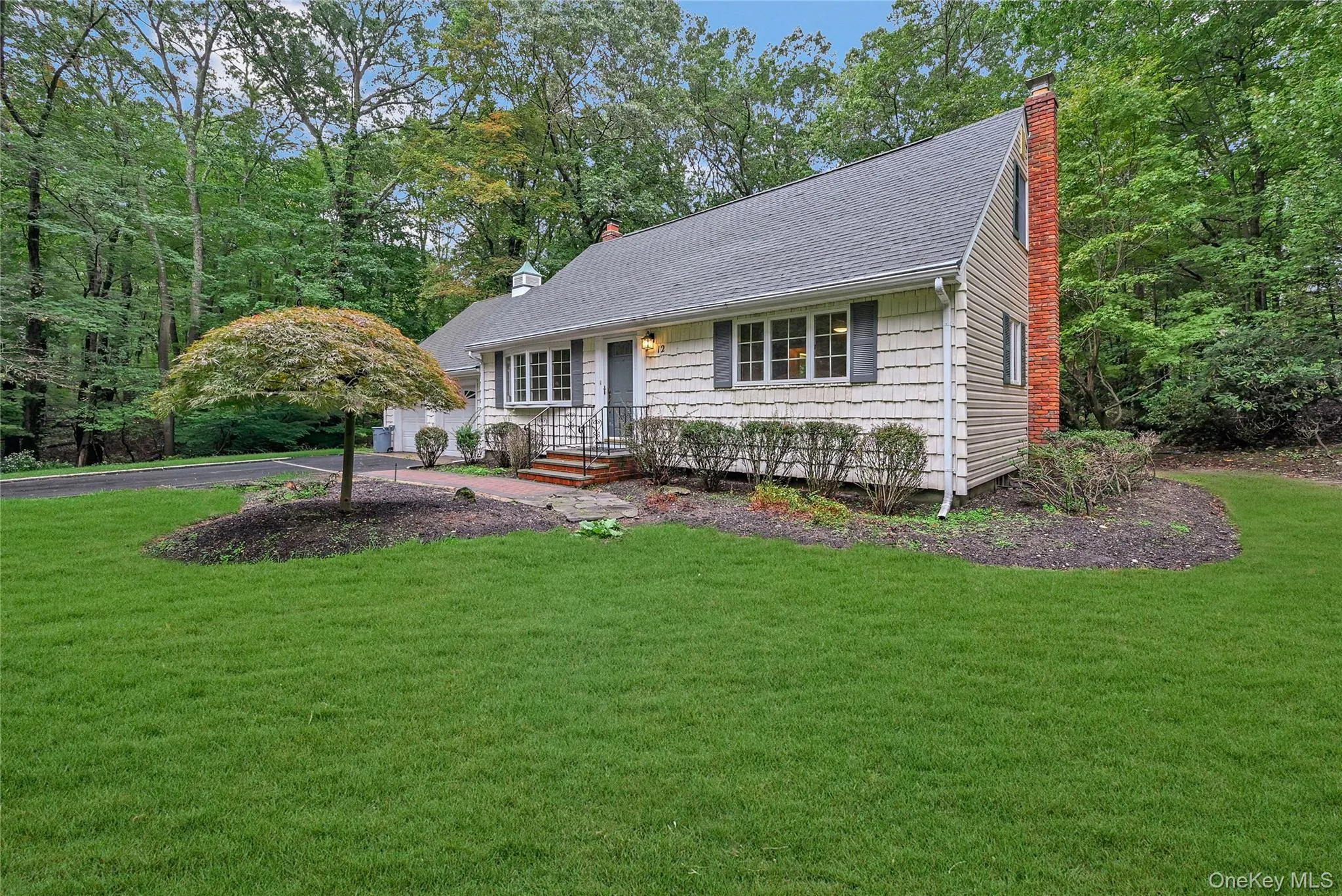 View of front facade with a shingled roof, a front yard, and a chimney View of front facade with a shingled roof, a front yard, and a chimney