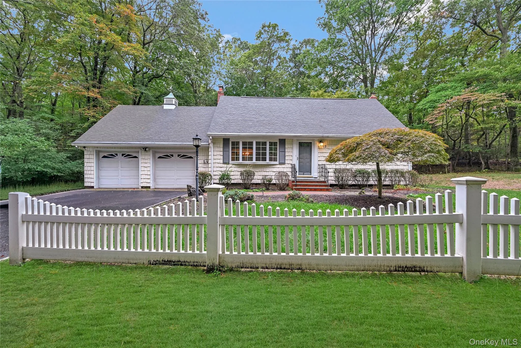 View of front of house with a chimney, a fenced front yard, covered porch, and asphalt driveway View of front of house with a chimney, a fenced front yard, covered porch, and asphalt driveway