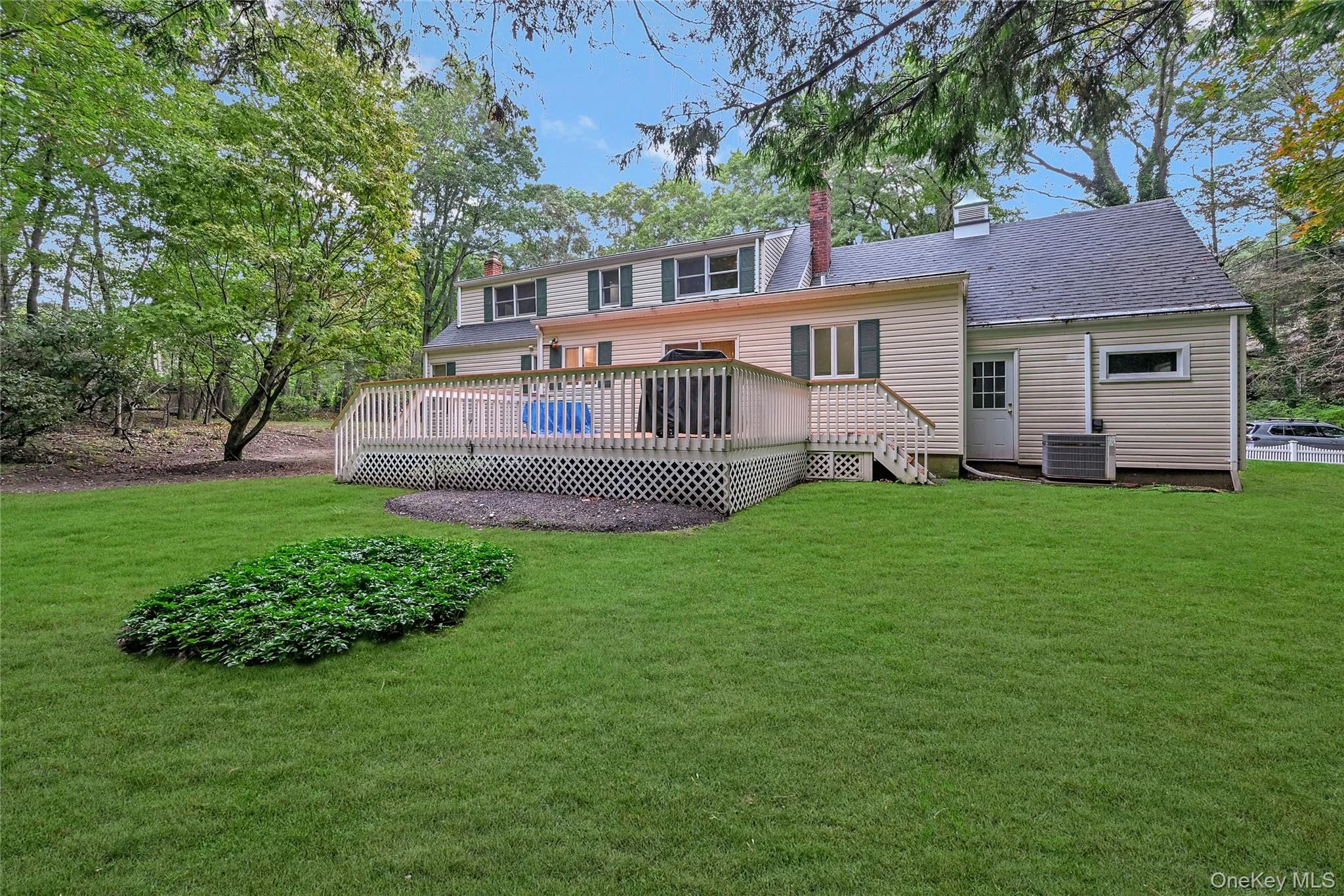 Rear view of property featuring a wooden deck, a lawn, and a chimney Rear view of property featuring a wooden deck, a lawn, and a chimney