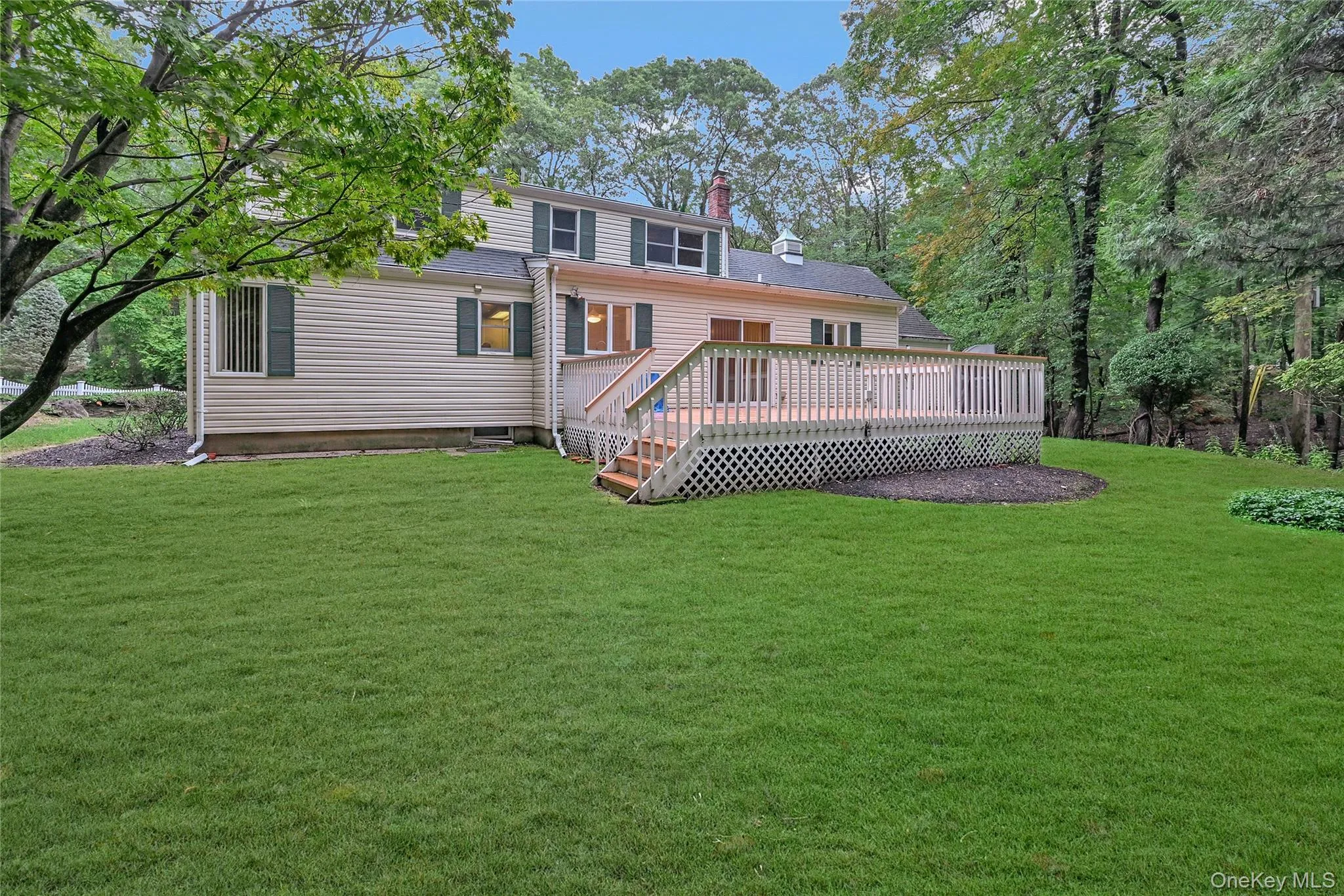 Rear view of property featuring a chimney, a yard, and a deck Rear view of property featuring a chimney, a yard, and a deck