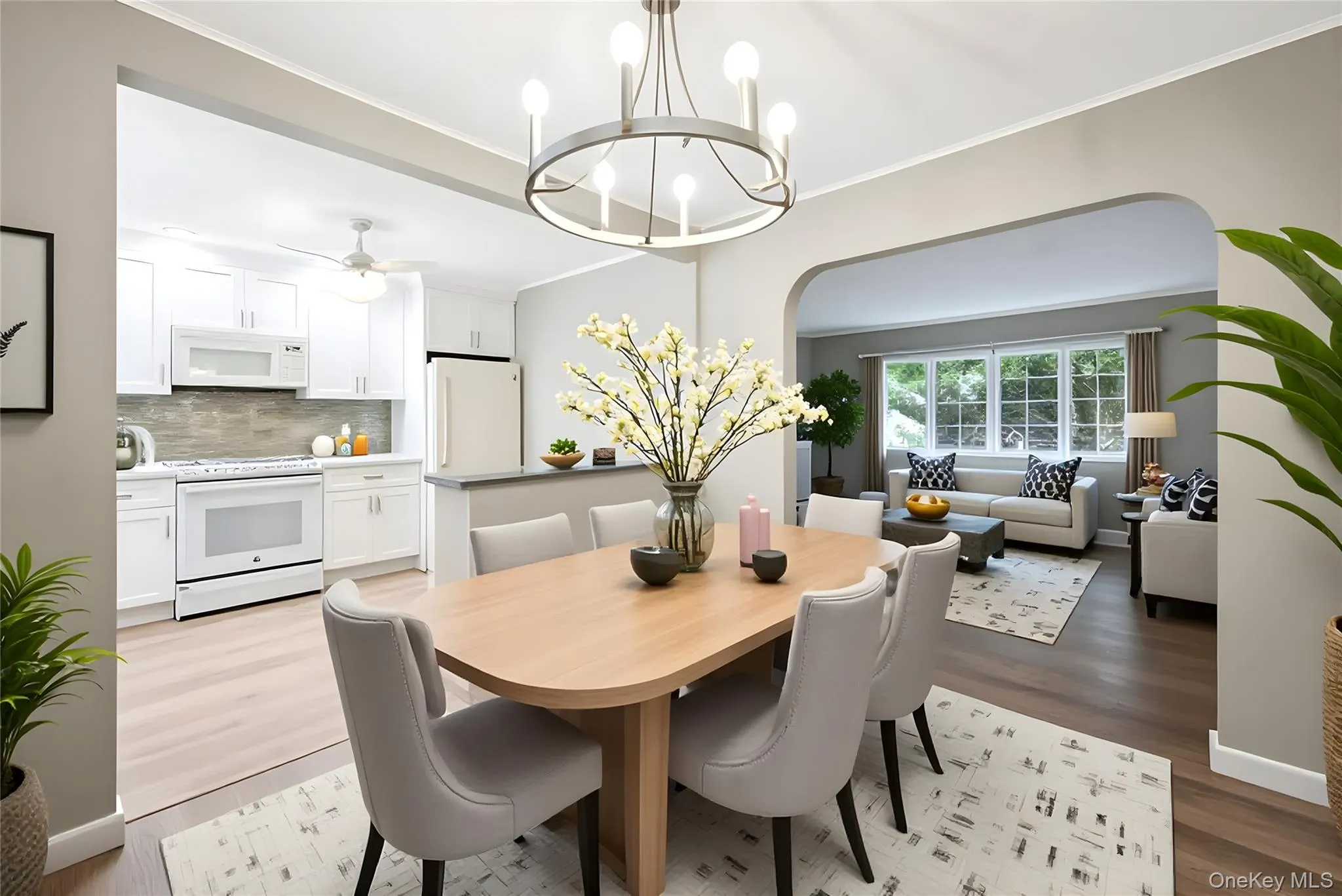 Dining room with ornamental molding, light wood-style flooring, arched walkways, and a chandelier Dining room with ornamental molding, light wood-style flooring, arched walkways, and a chandelier